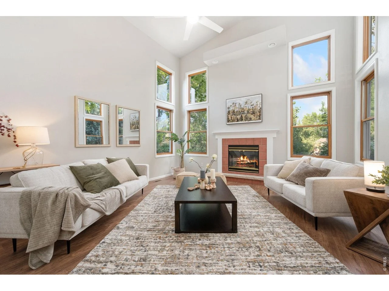 Living room with couches, coffe table, fireplace and many windows.