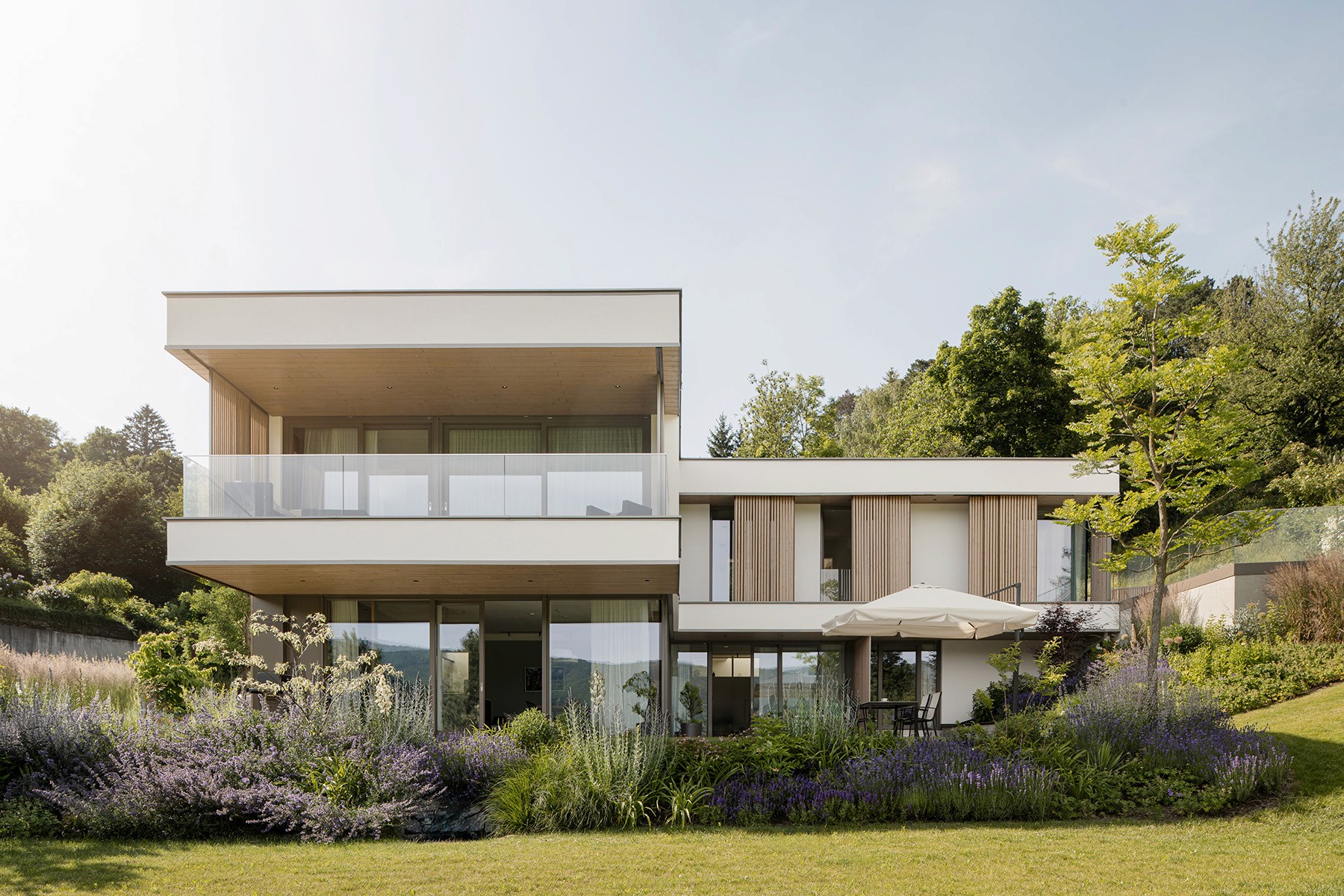 Modernes Wohnhaus mit großzügiger Terrasse und naturnah bepflanztem Garten mit Stauden und Gräsern.