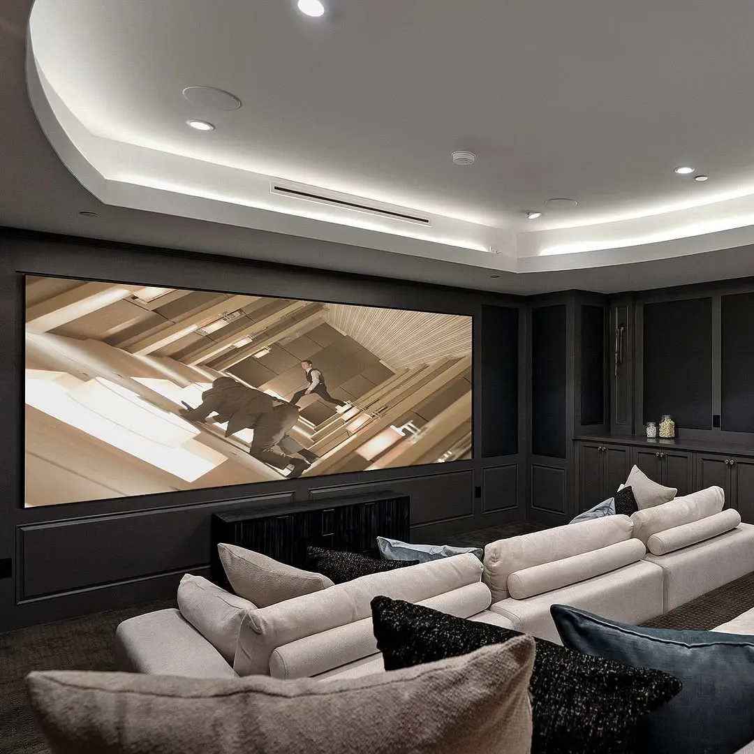 Luxurious home theater with tiered white seating, a large screen, and ambient ceiling lights.