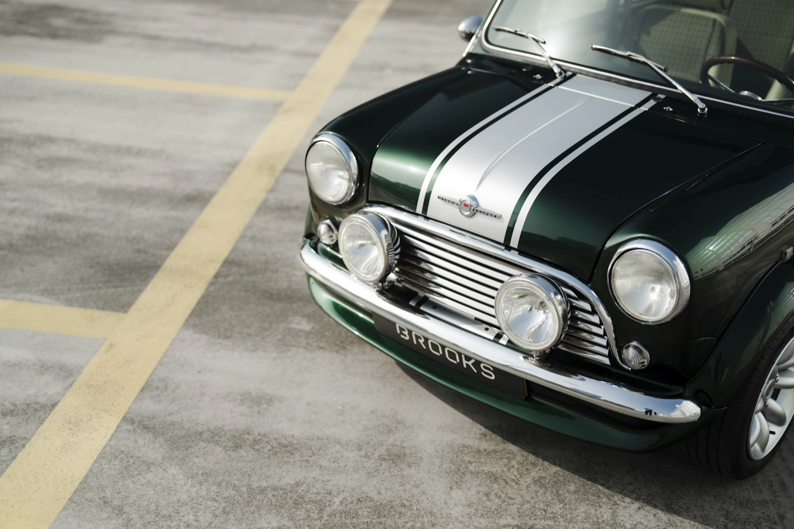 A close-up view of a classic black car with a silver stripe, parked on a light-colored surface.
