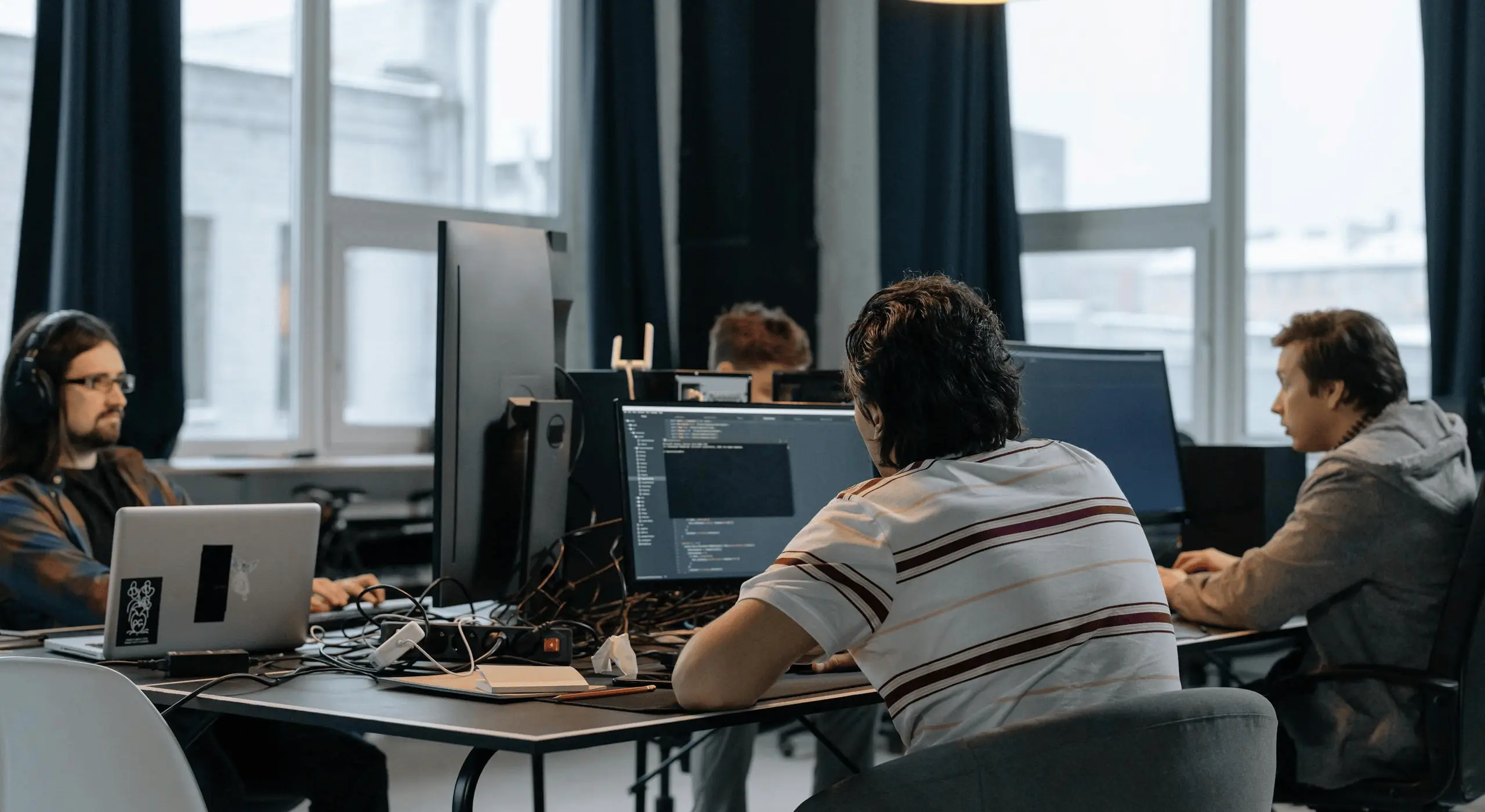 Team of developers working together on computers in a modern tech office.