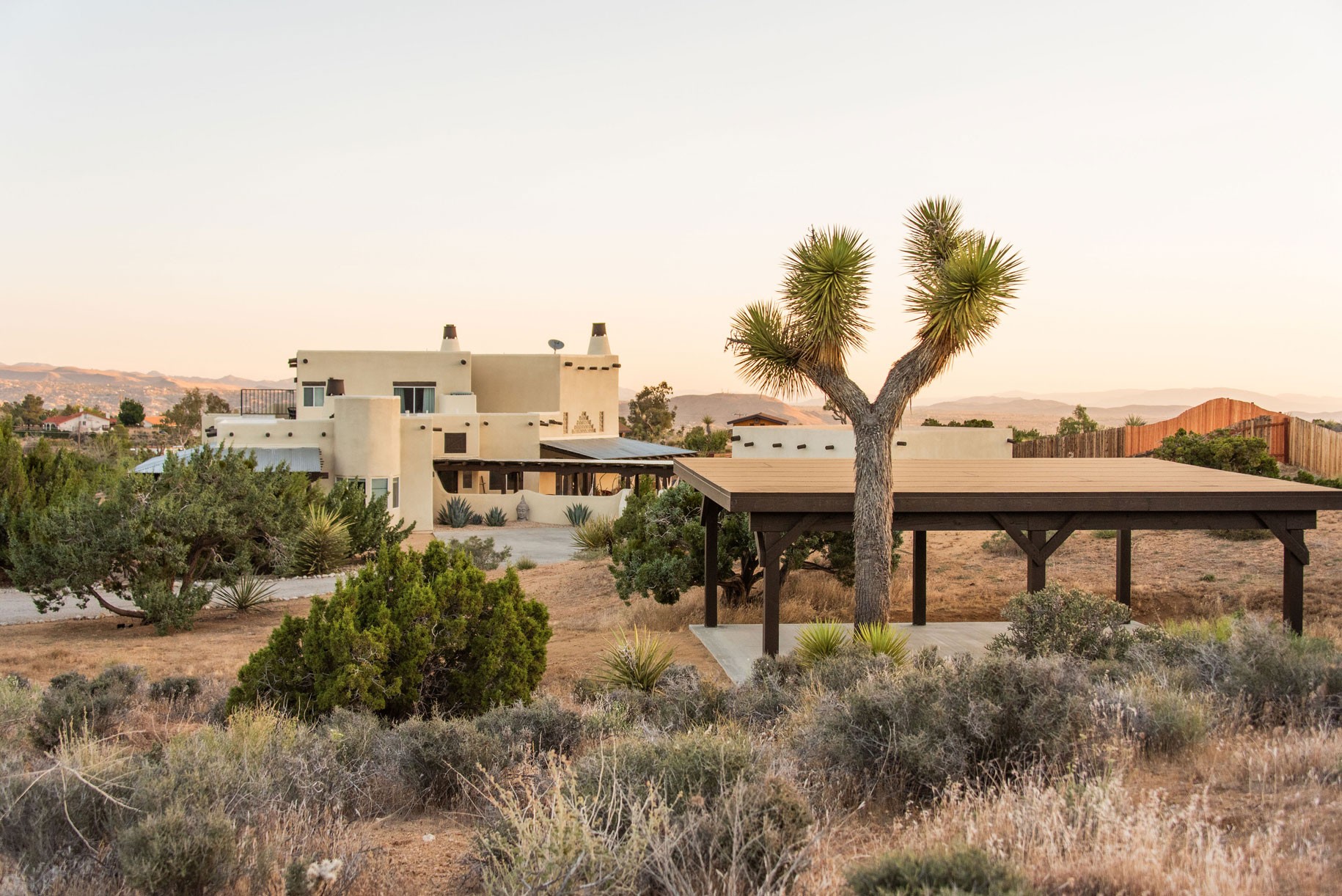 Desert retreat location, featuring a white villa surrounded by desert shrubs and a wide open sky.