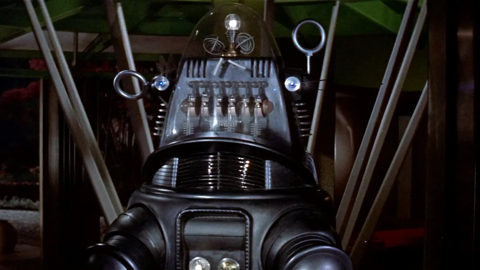 The image features a classic humanoid robot with a transparent dome head and intricate metallic detailing, standing in a futuristic setting with visible mechanical components and a striking use of lighting.