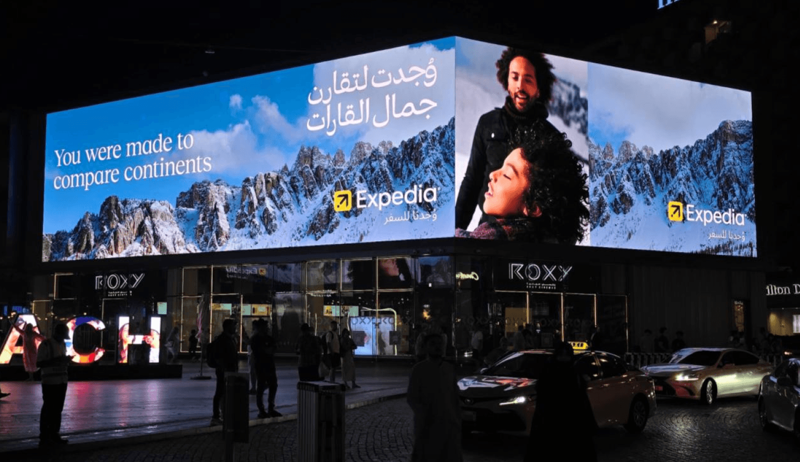 a man walking down a street past a large poster