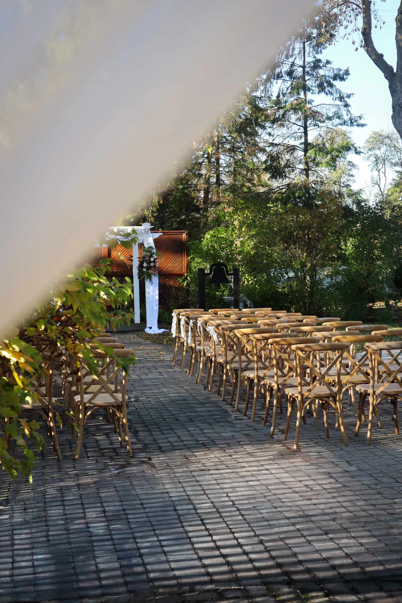 Row of crossback chairs with white satin ribbon bows cobblestone