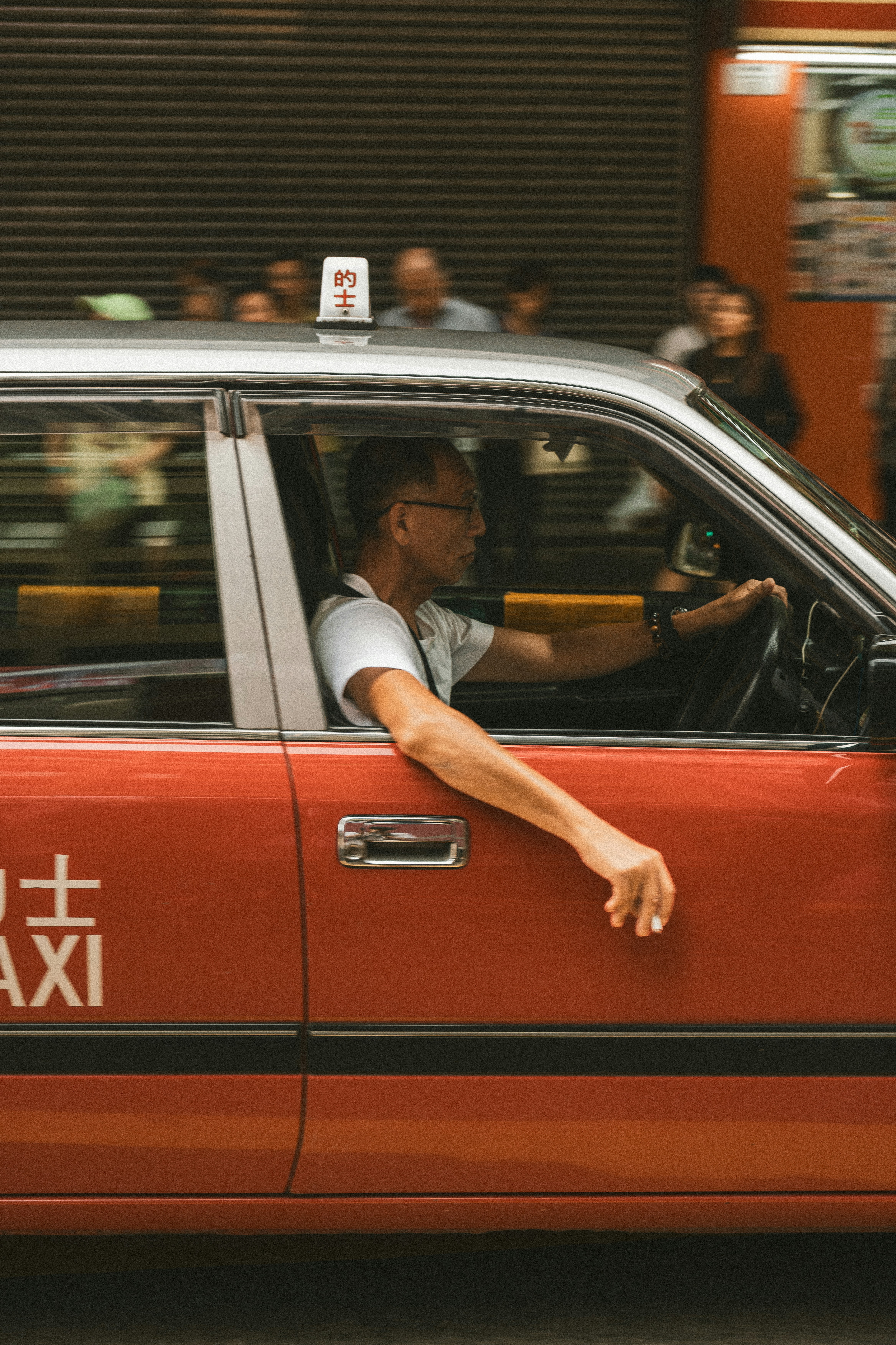 Man driving a red taxi in a city