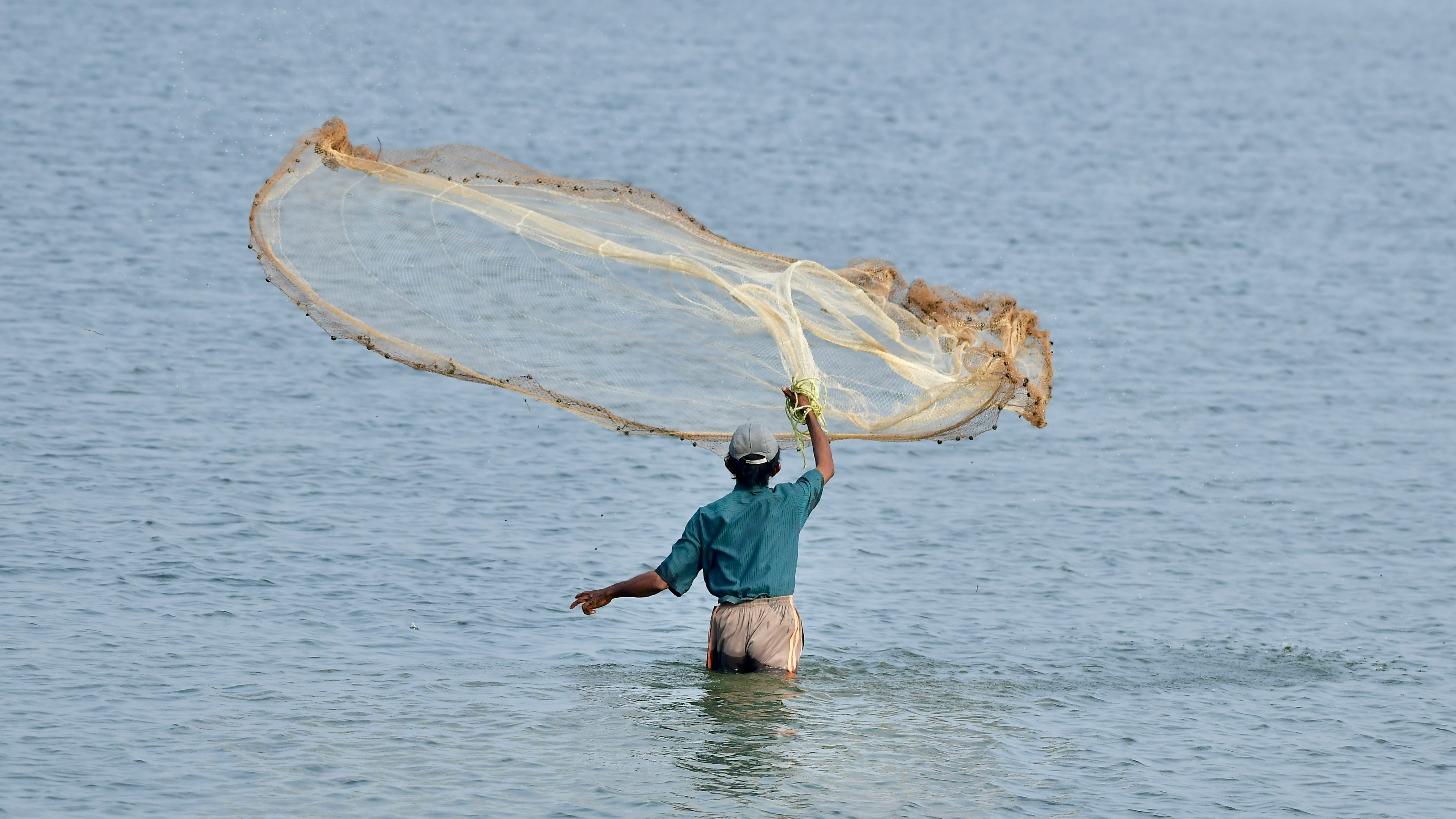 a man wading in the water with a fishing net