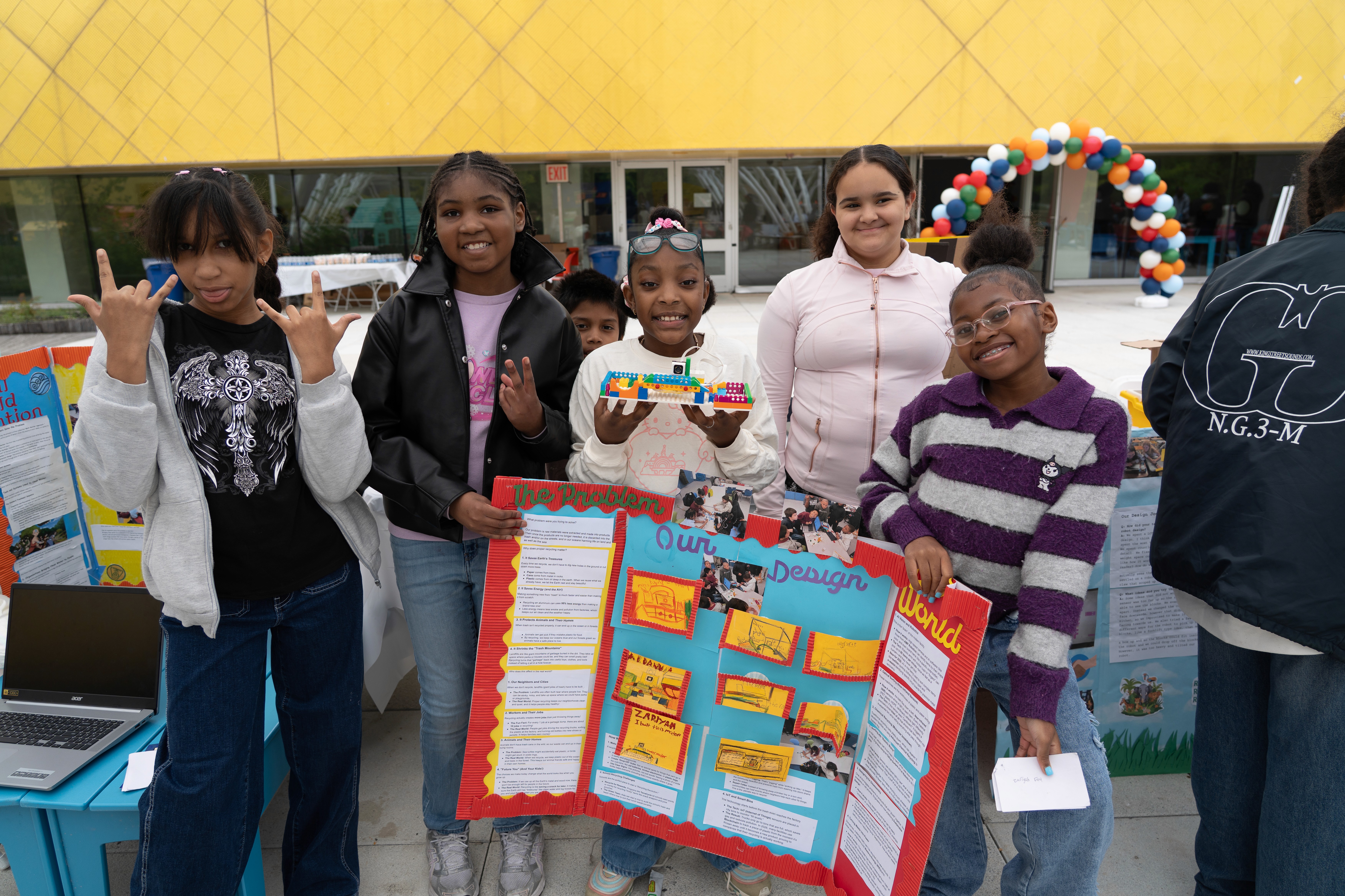 Participants hold their Lego model and posterboard up