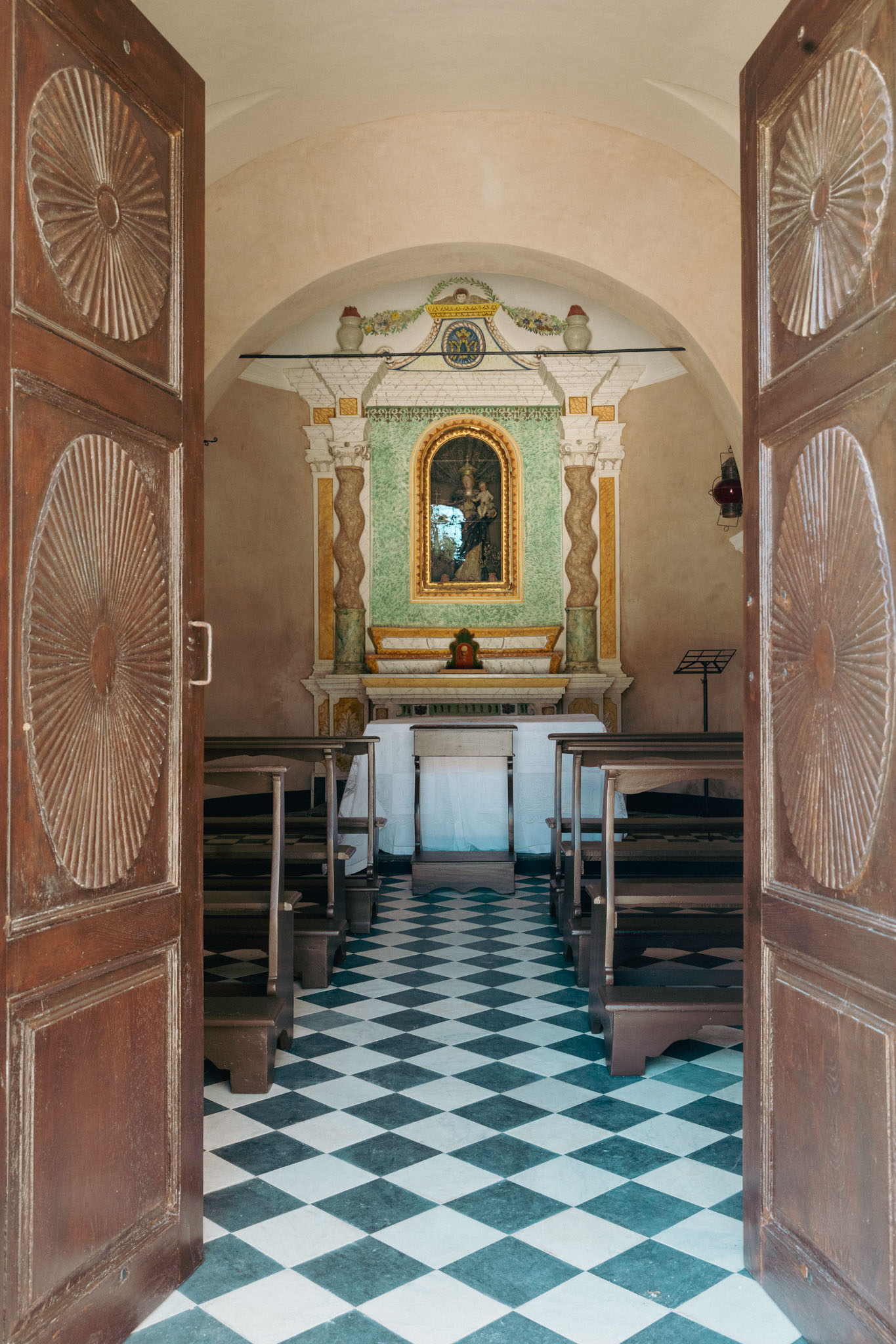 A bride in a white lace wedding dress holds a colorful bouquet of pink, yellow, and orange flowers.