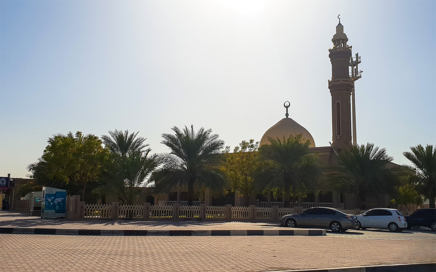 Serene neighborhood mosque in Nad Al Hamar surrounded by palm trees, ideal for family-oriented living.