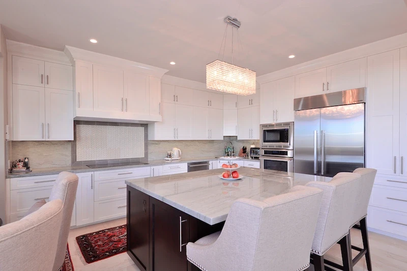 Modern white kitchen with central island and bar chairs in Harbor Ridge Transitional Remodel.