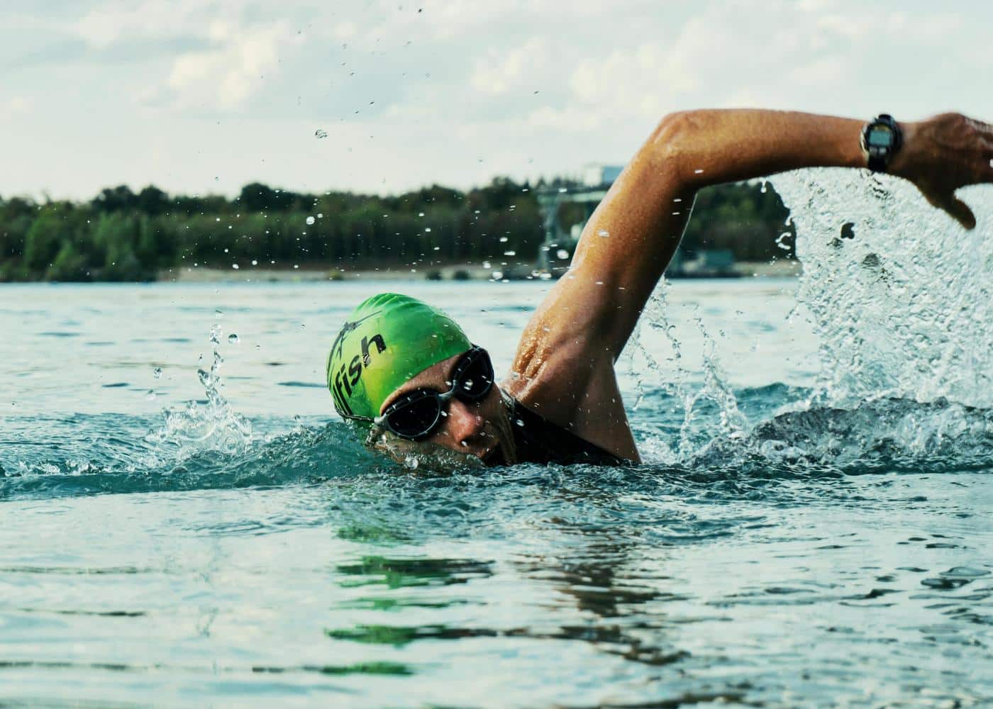 Man swimming in a lake while wearing a waterproof fitness tracker