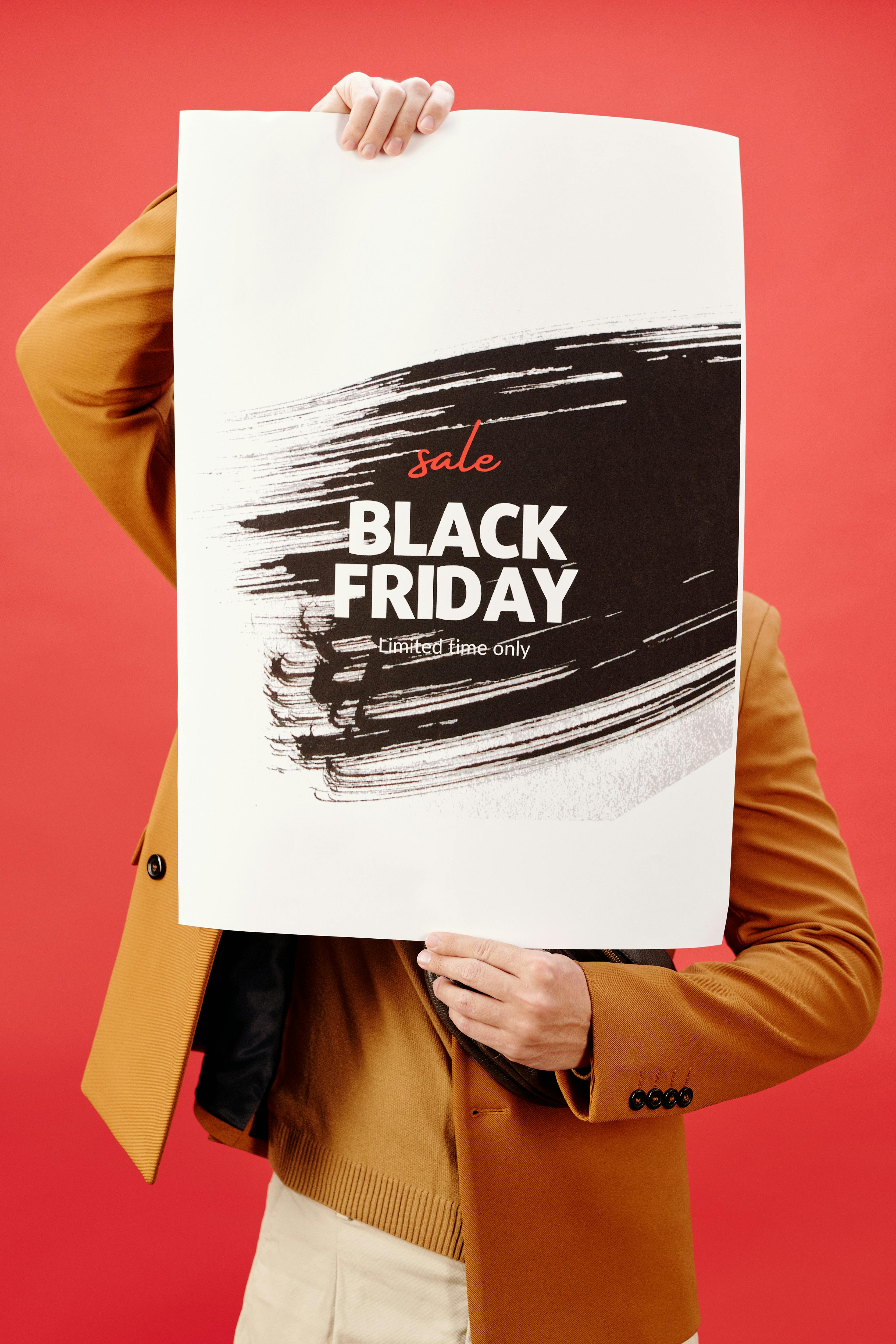 individual-holding-a-vibrant-black-friday-sale-poster-against-a-red-background. - max-fischer (pexels)