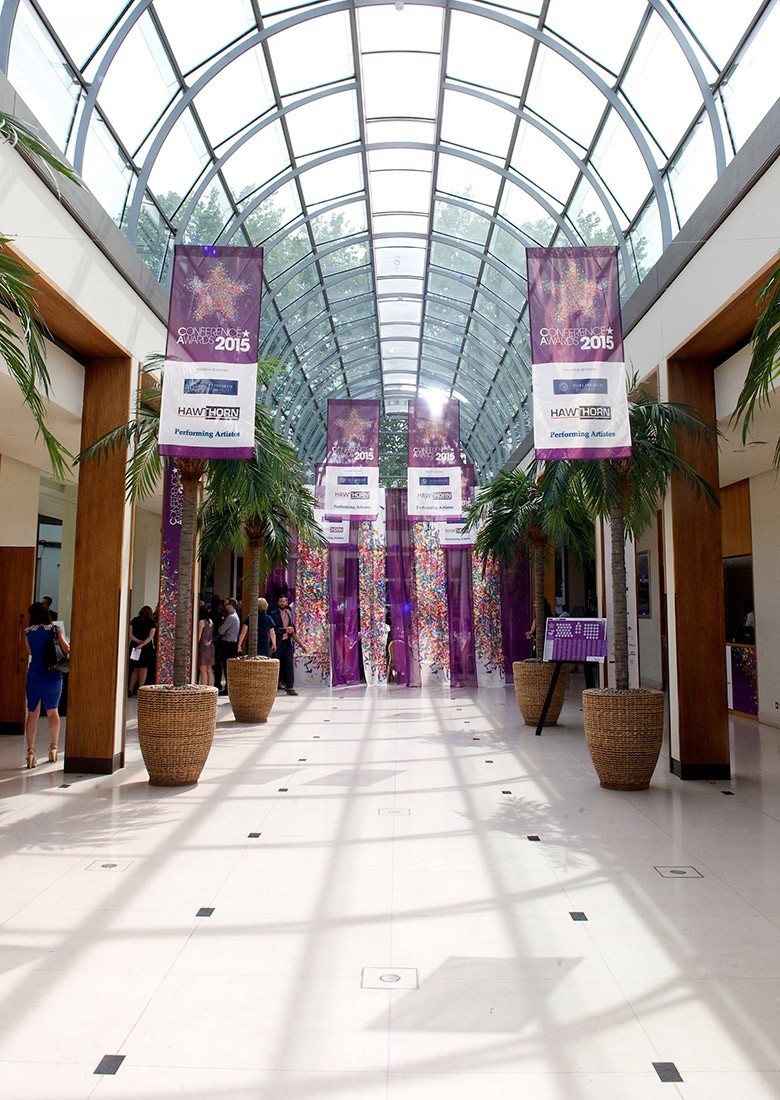 Large purple branded banners hanging from the ceiling in a luxury venue at a conference awards event.