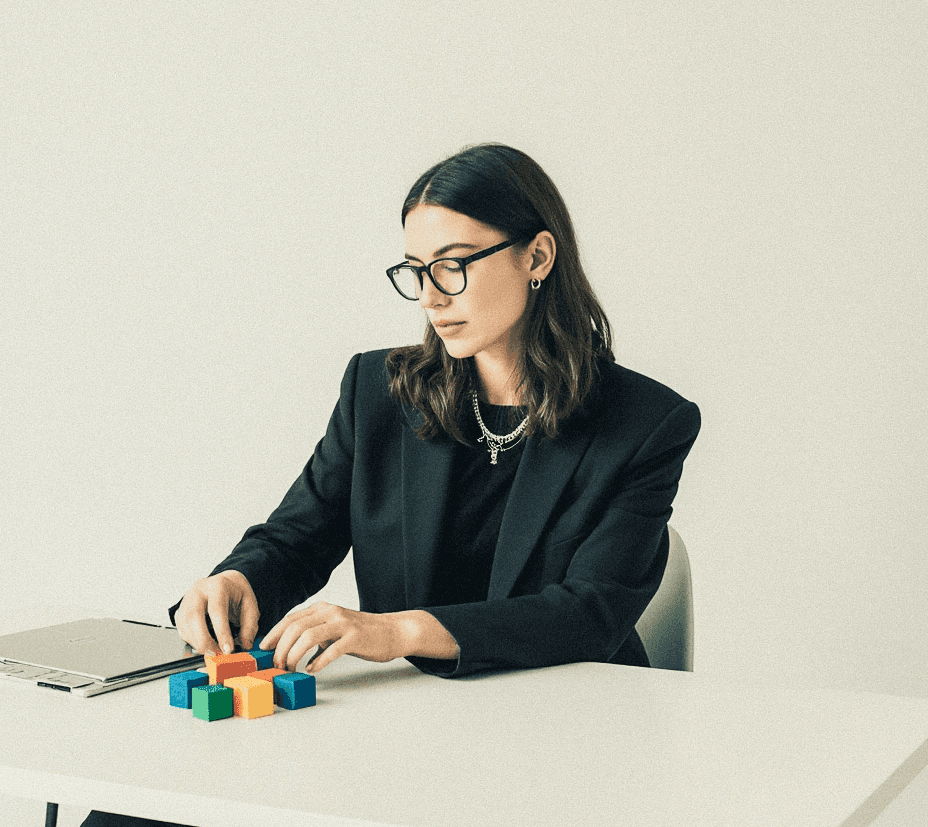 Women with a suit sitting at a desk playing with blocks