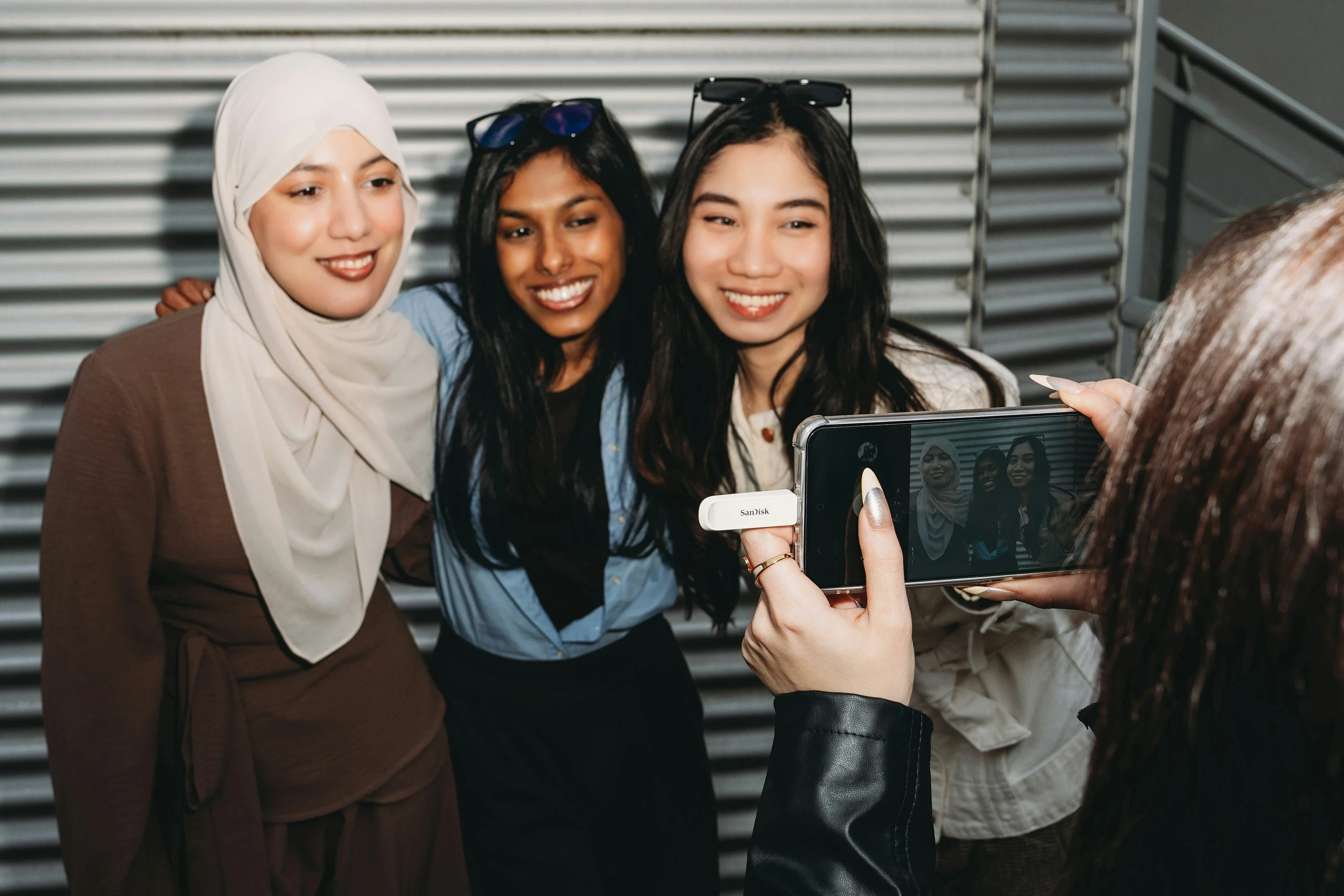A person photographs three smiling women with a smartphone