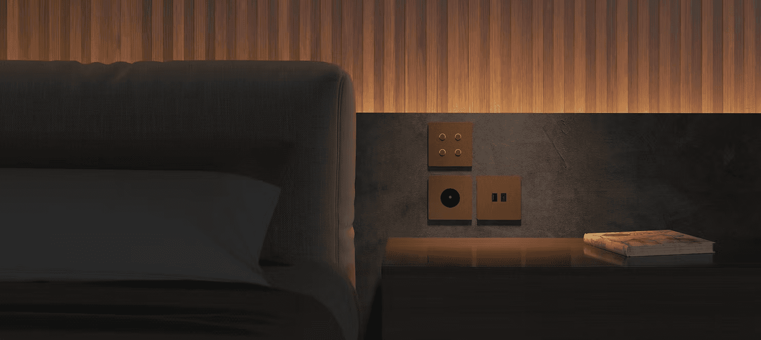 Modern light switches and a book beside a bed.