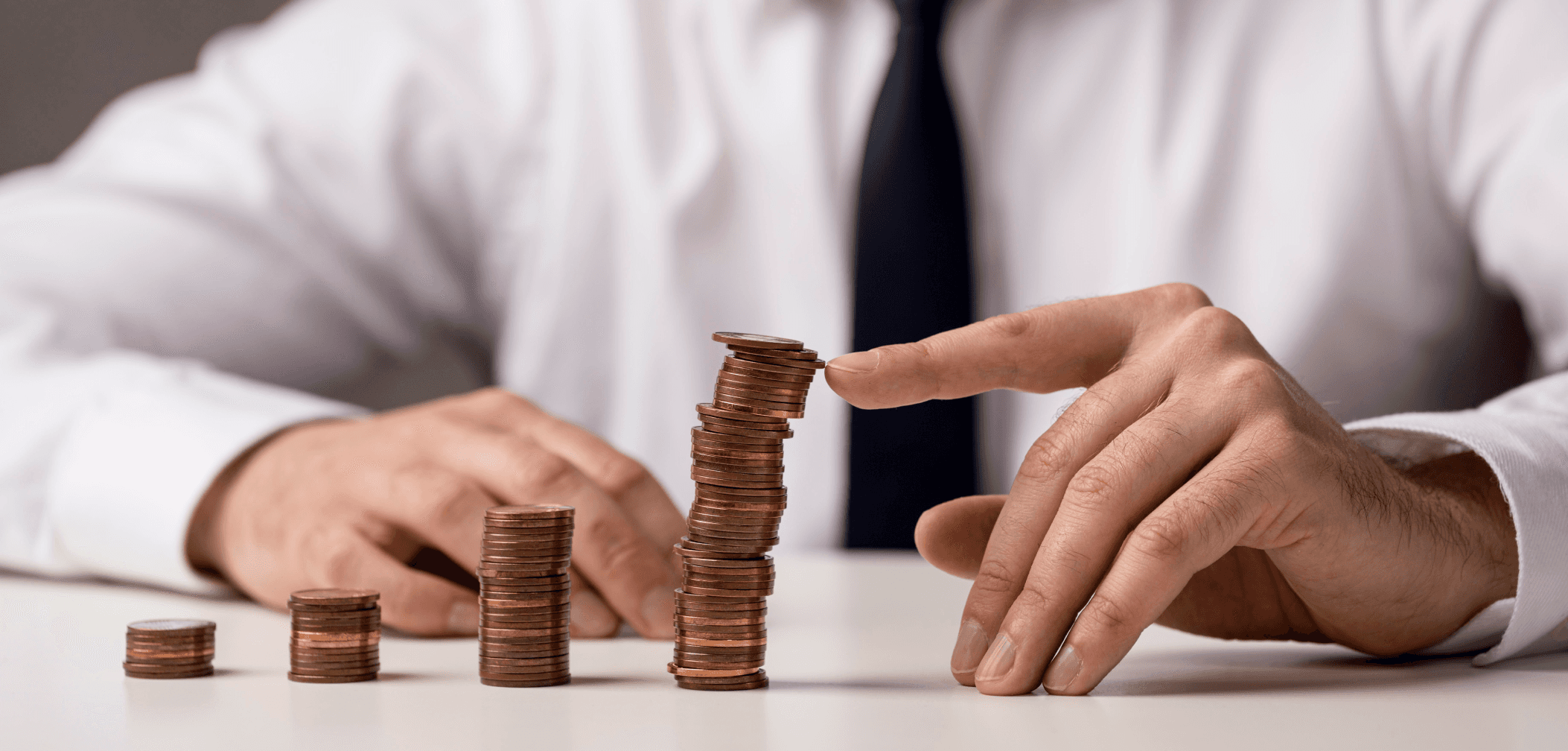 Close-up of stacked coins being arranged to represent usability testing costs, budgeting for UX research, and the value of investing in user feedback.