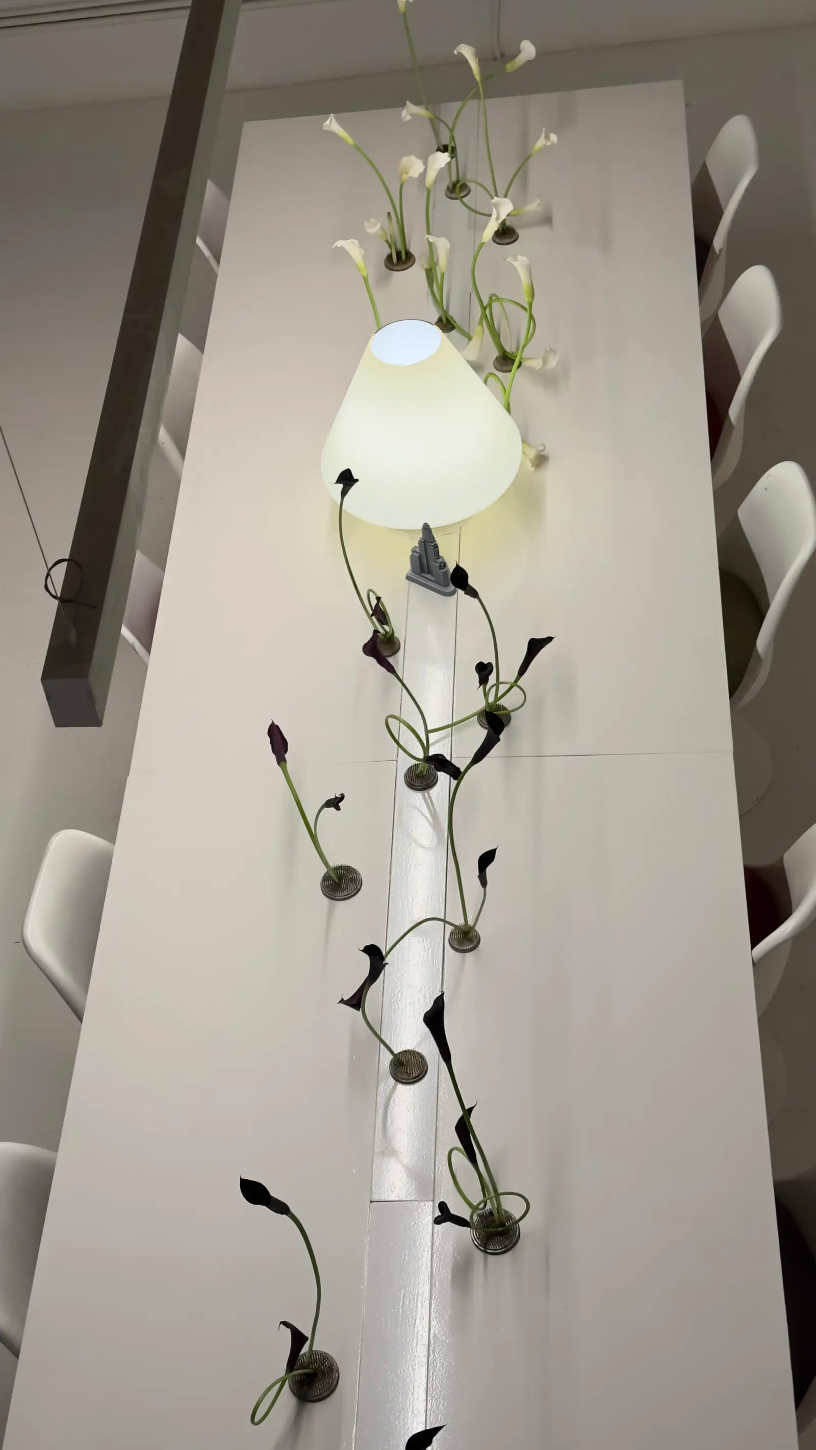 Vista aérea de mesa larga decorada con secuencia de calas blancas y negras, lámpara de diseño y techos altos.