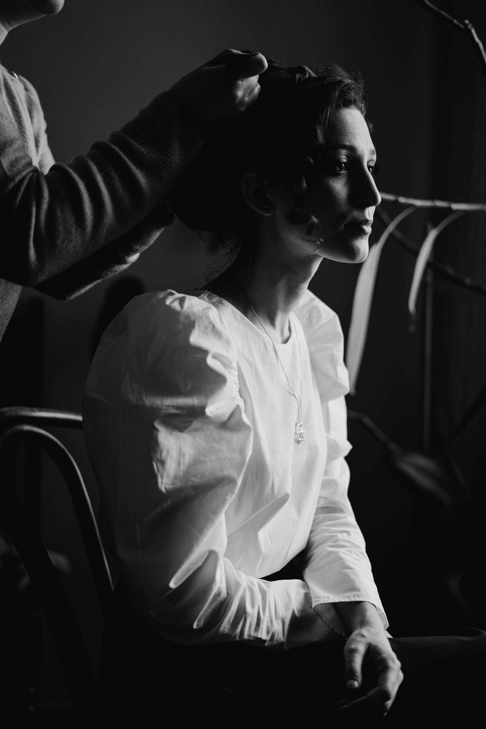 A woman sits in a salon chair while a man styles her hair, showcasing a professional hairdressing interaction