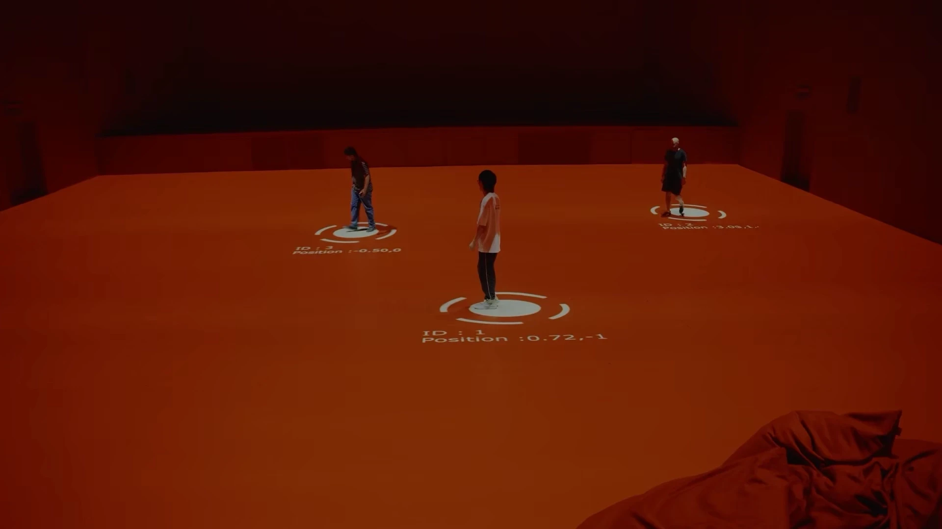 Three people on an orange floor with projected IDs and positions