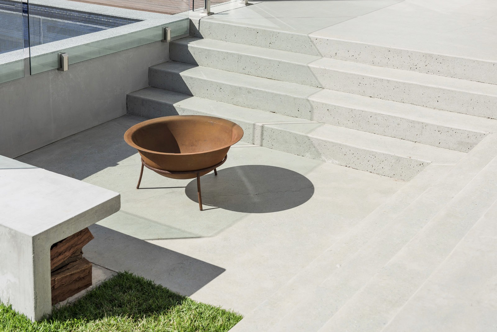 Outdoor concrete steps and pool edge with metal fire bowl on patio