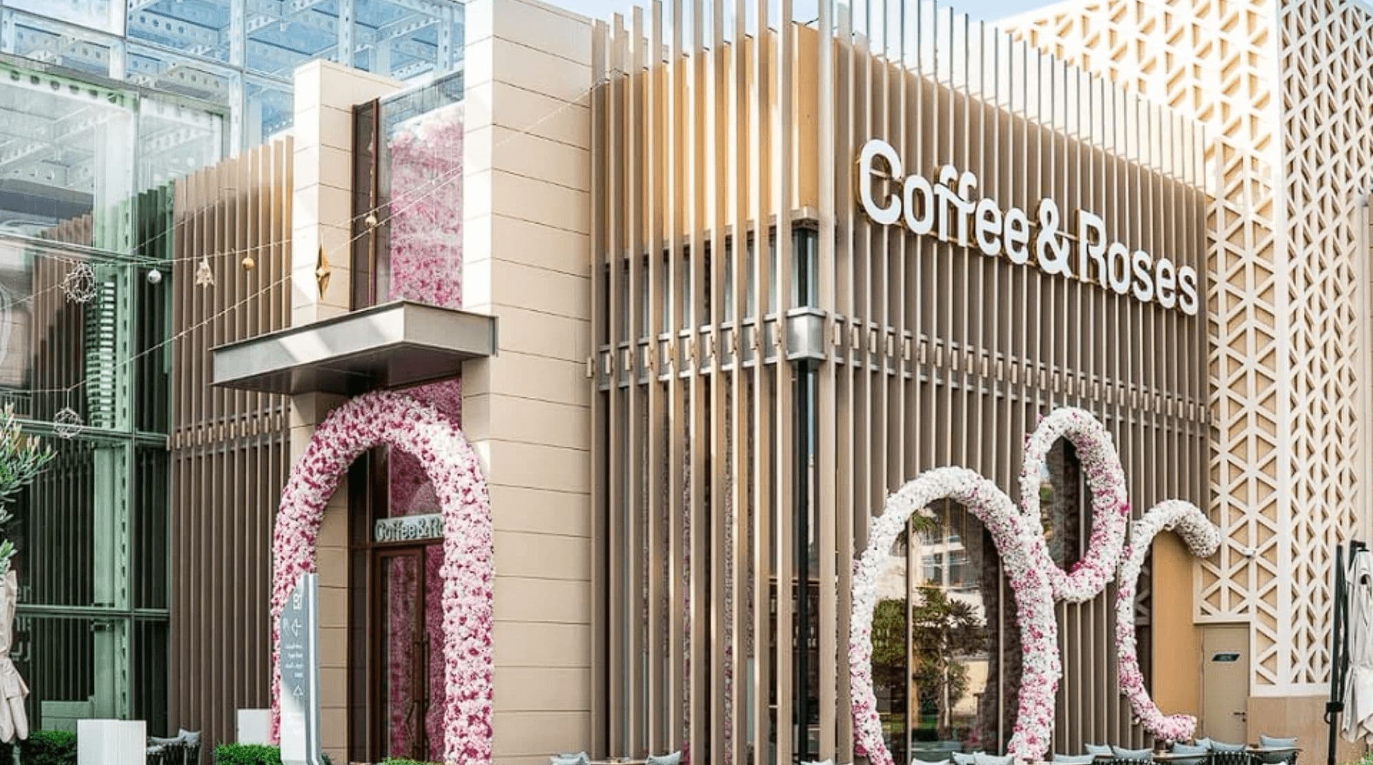 Coffee and Roses breakfast place in Dubai with a modern, brown building and pink archways and decor.