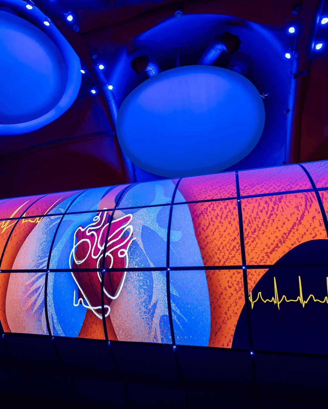 A BBC news studio setup featuring a central desk, bright lighting, and large screens in the background.
