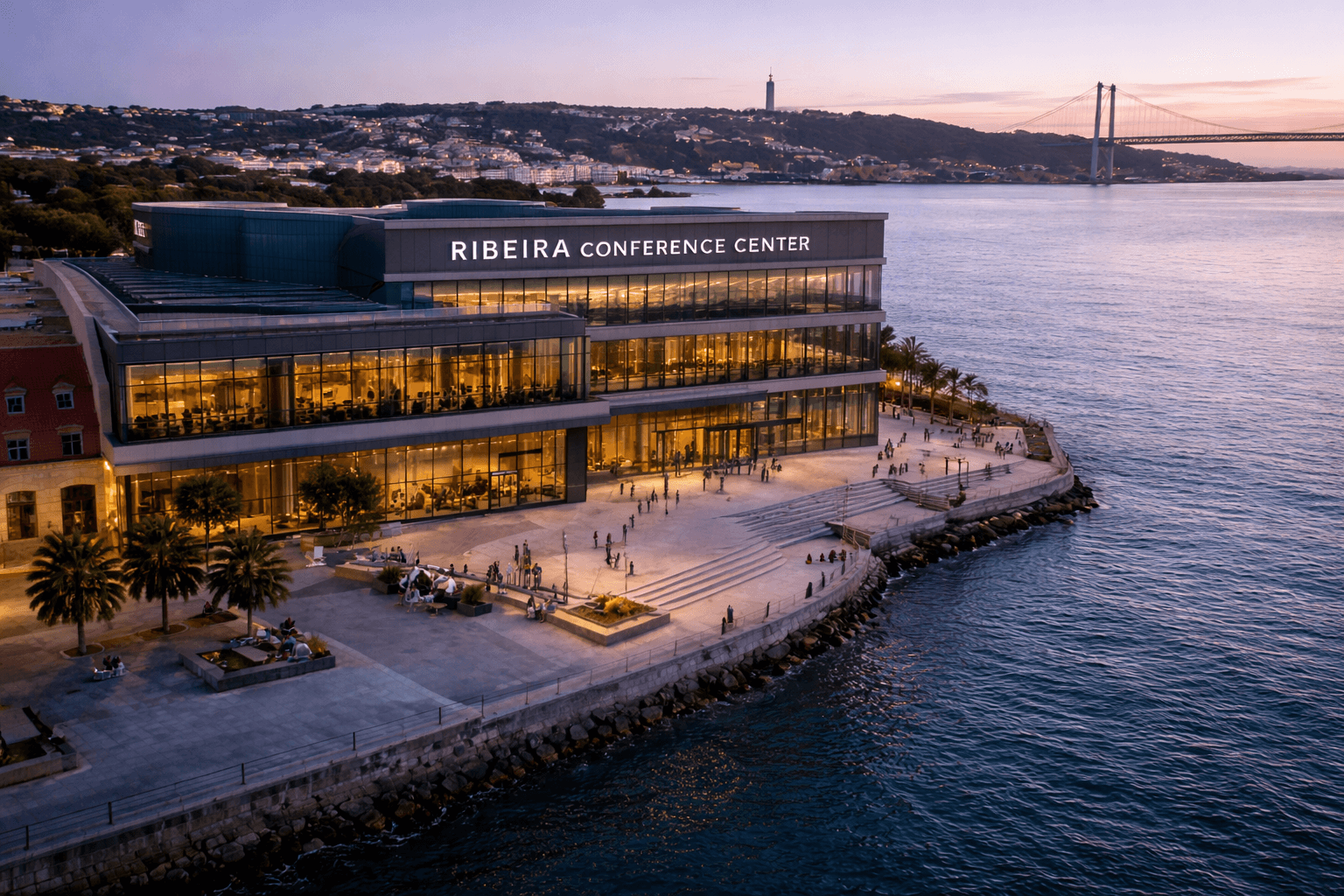 Aerial view of a modern riverside conference center in Lisbon with surrounding urban landscape.