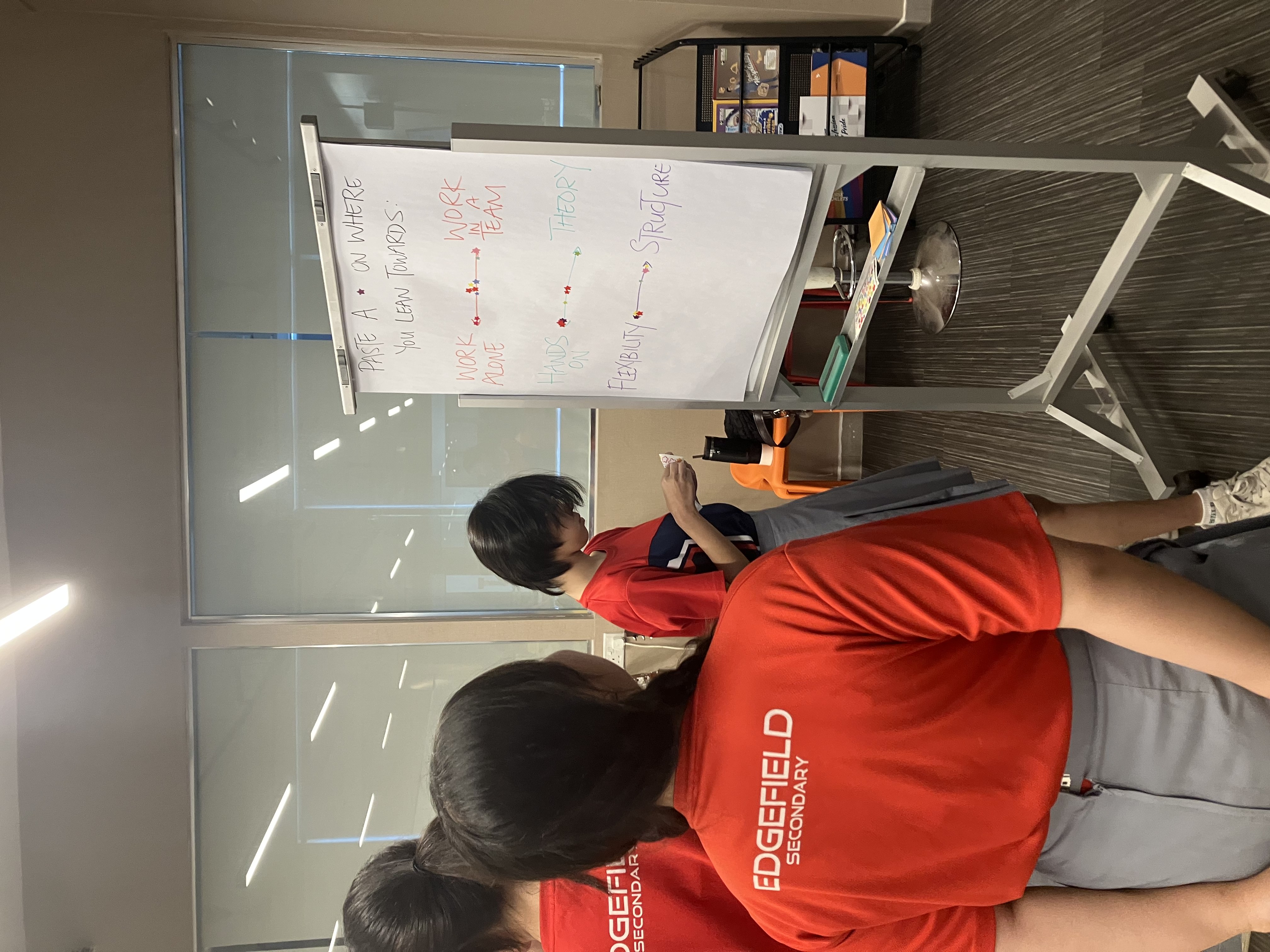 Smiling young man with short hair poses against a dark background, wearing a green button-up shirt.