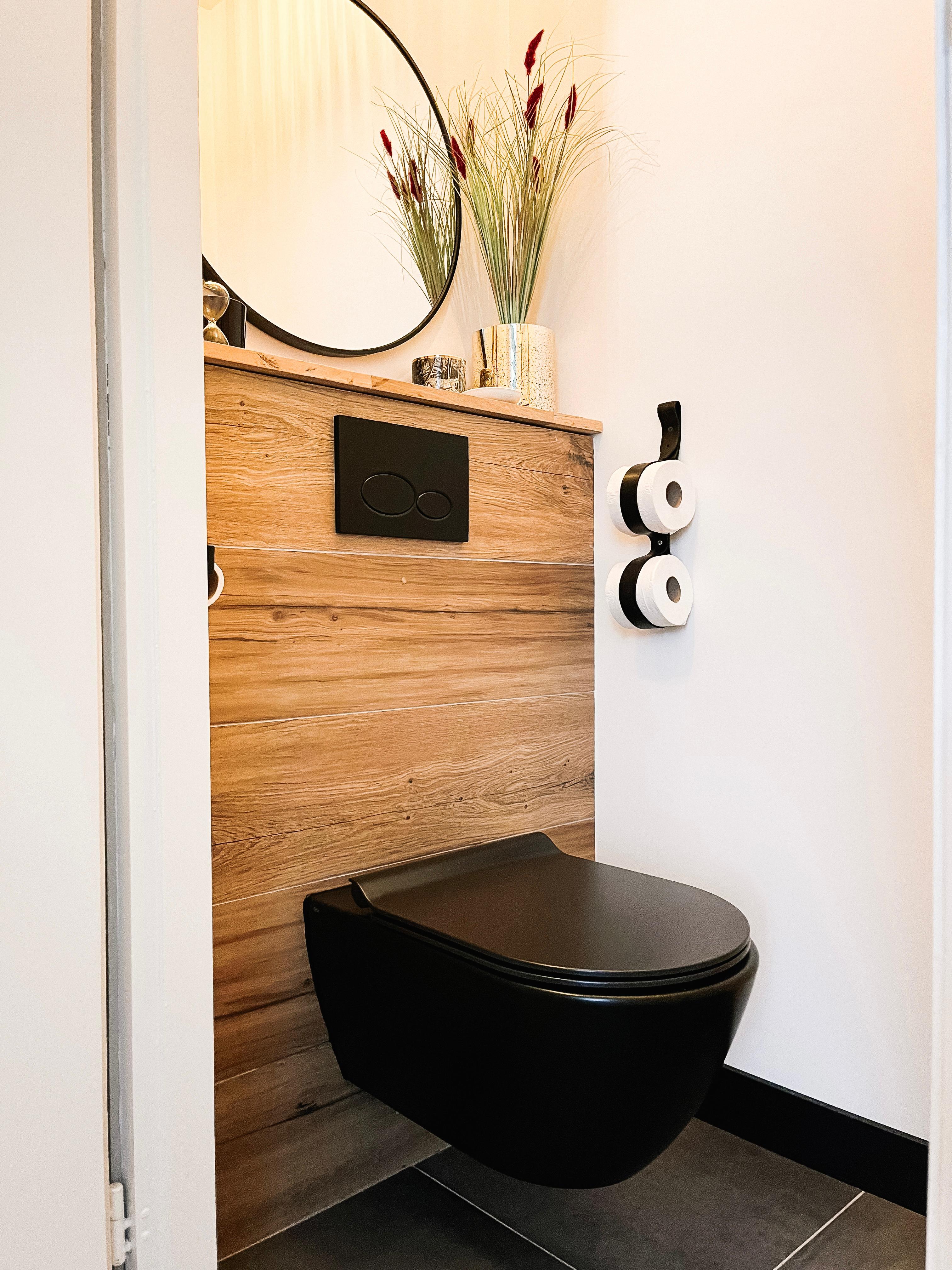 Modern toilet met hangtoilet, strakke houtlook tegels en minimalistisch design. Het kleine toilet heeft een efficiรซnt ruimtegebruik, een inbouwreservoir en een moderne badkamerstijl met lichte, neutrale kleuren.