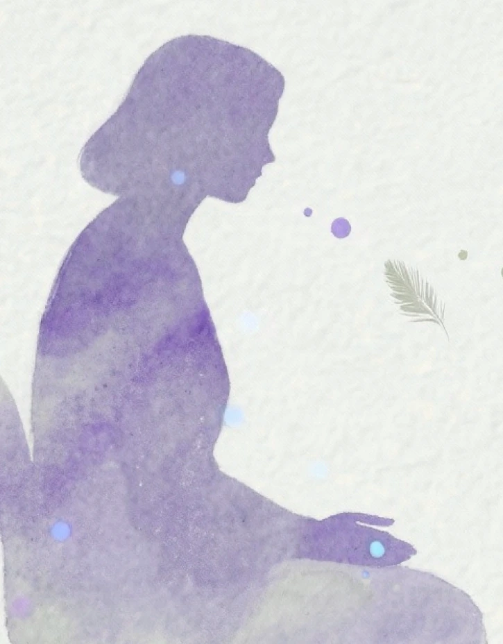 A person with curly hair sits at a desk, working on a laptop in a cozy, well-lit environment.