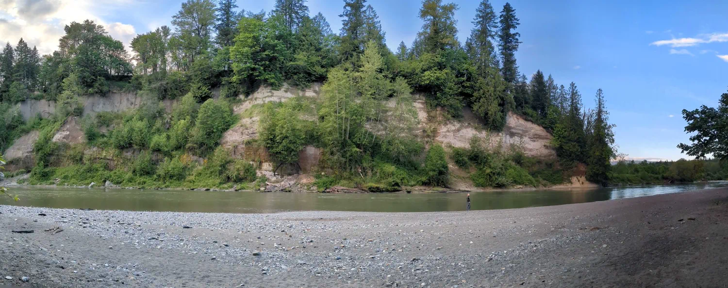 Scenic riverbank and forested cliffs along the trails at River Meadows County Park near Arlington, Washington.
