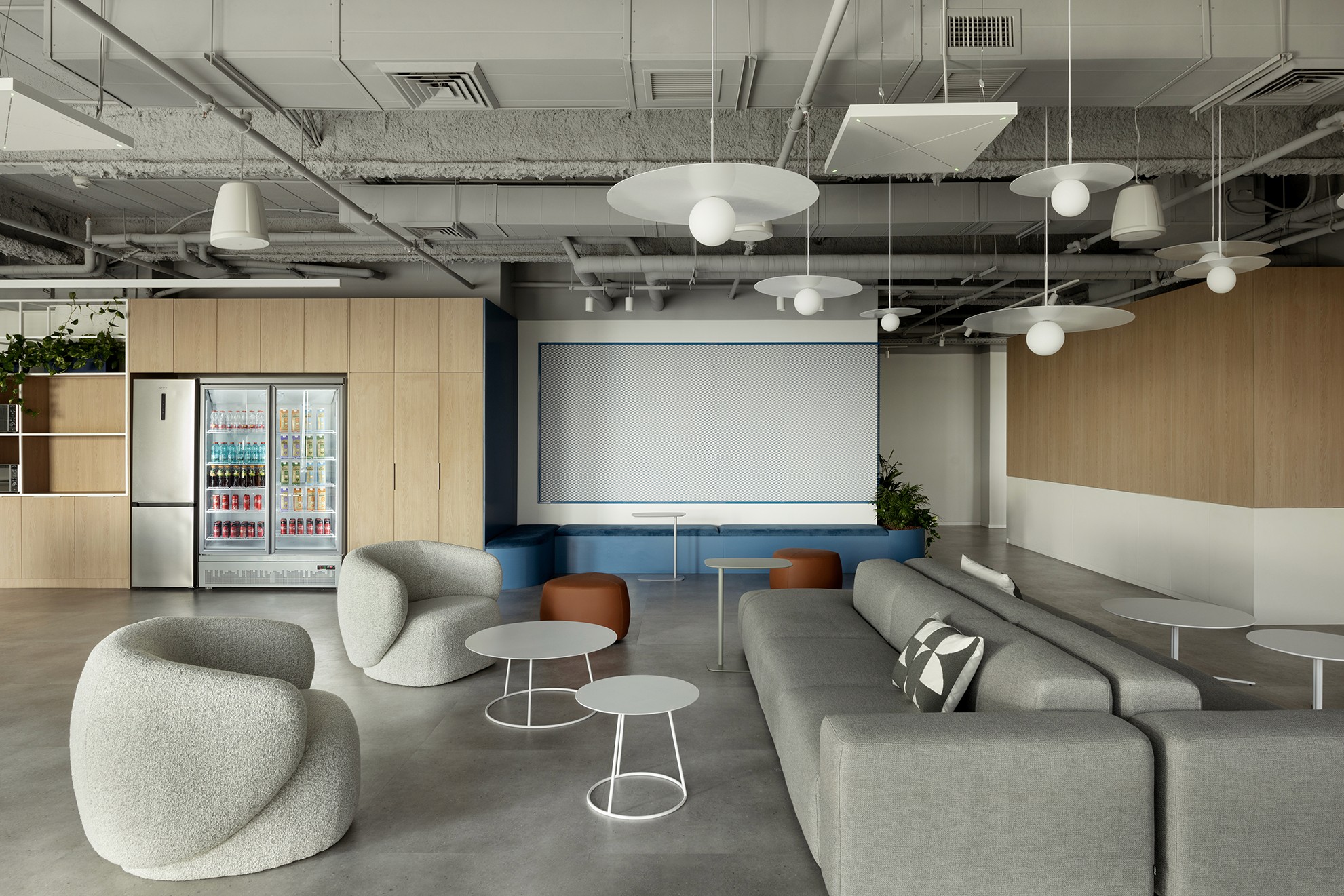 אזור הקפיטריה והמטבחון: שילוב בין נגרות עץ אלון בהירה, ריצוף בטון מוחלק ותקרה תעשייתית חשופה למראה נקי ומודרני