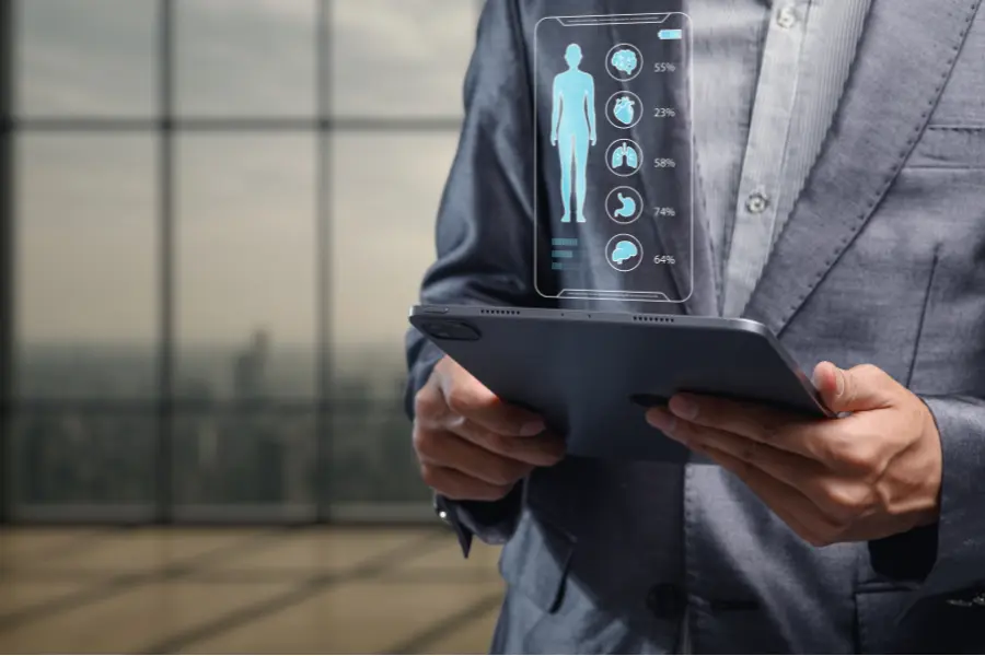 AI in medicine visualized as a professional holds a tablet projecting a holographic human body scan with organ health data percentages floating above the screen.