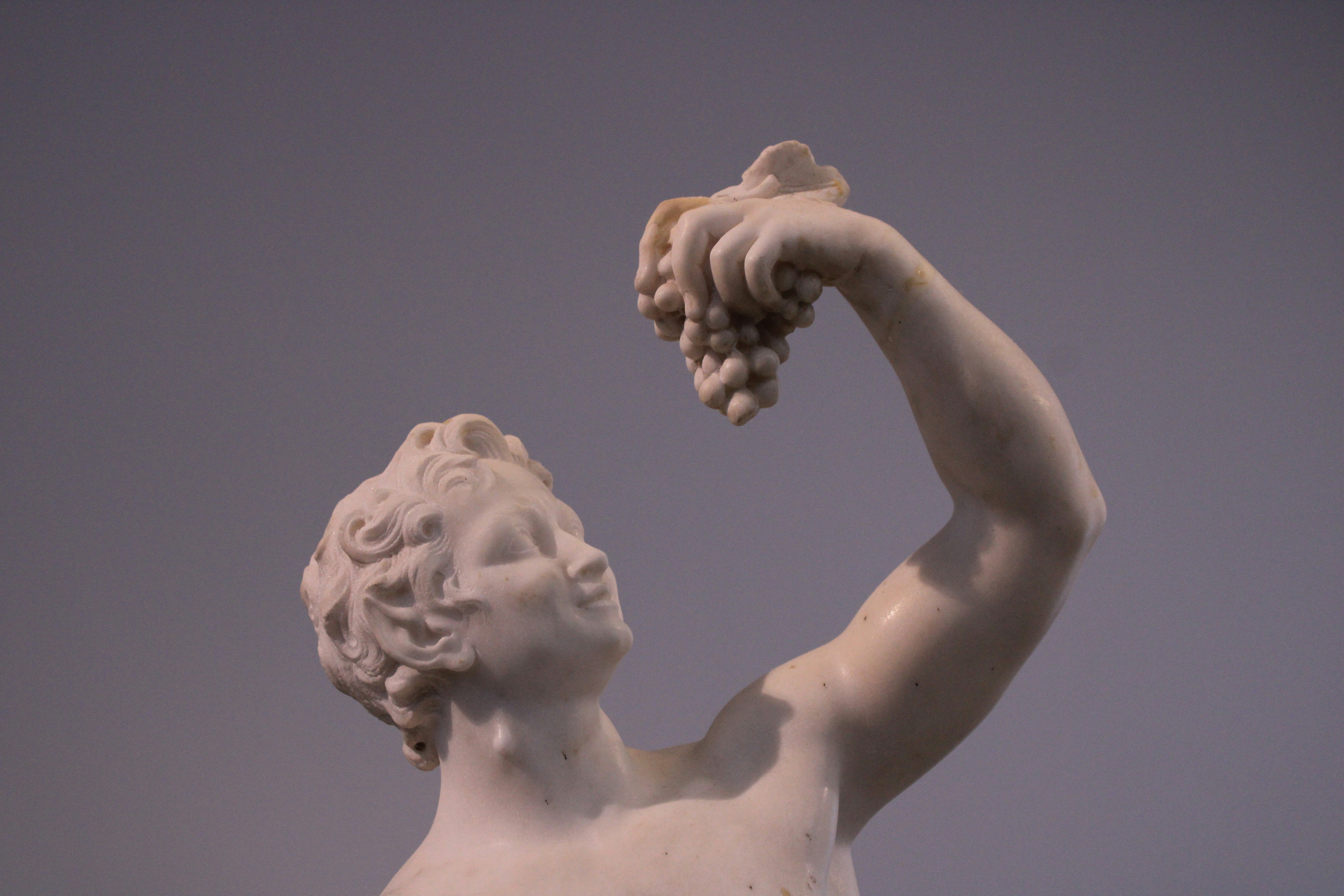 Marble statue of a young man holding grapes