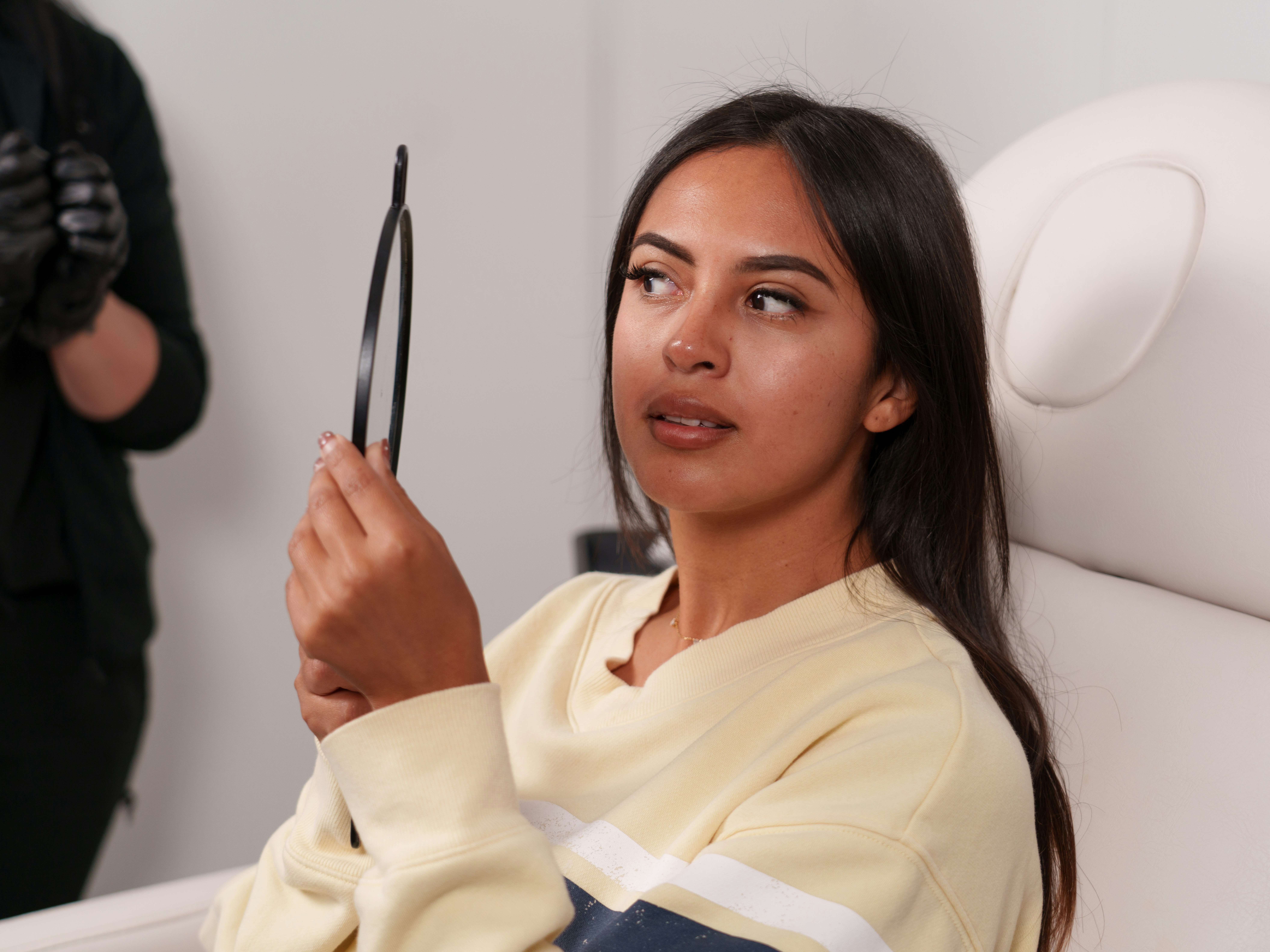 A woman in the recovery phase examining her healing progress while looking at her reflection in a mirror