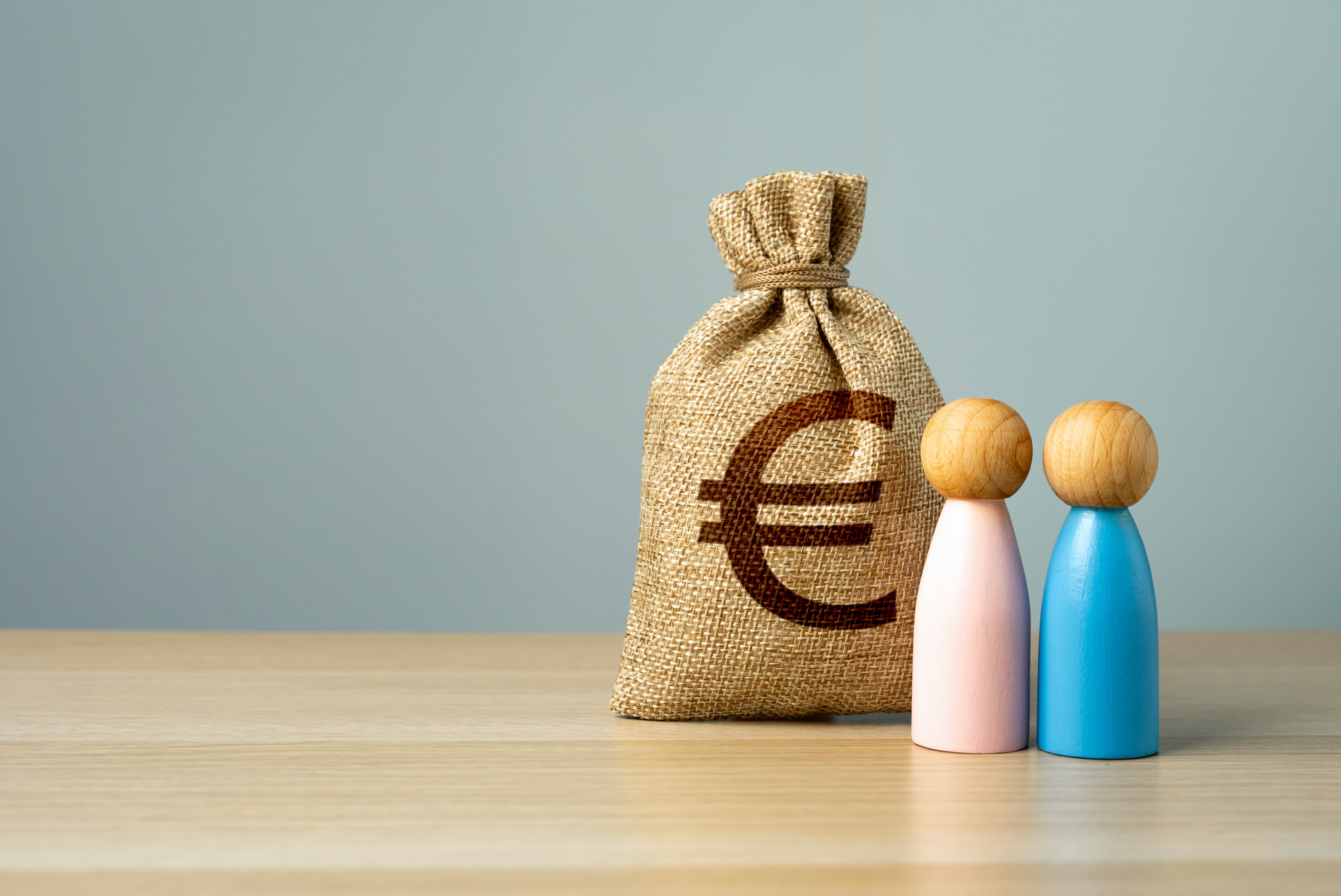 Jute geldzak met euroteken en houten poppetjes, symbool voor vermogen, gezin en financiële emigratieplanning.