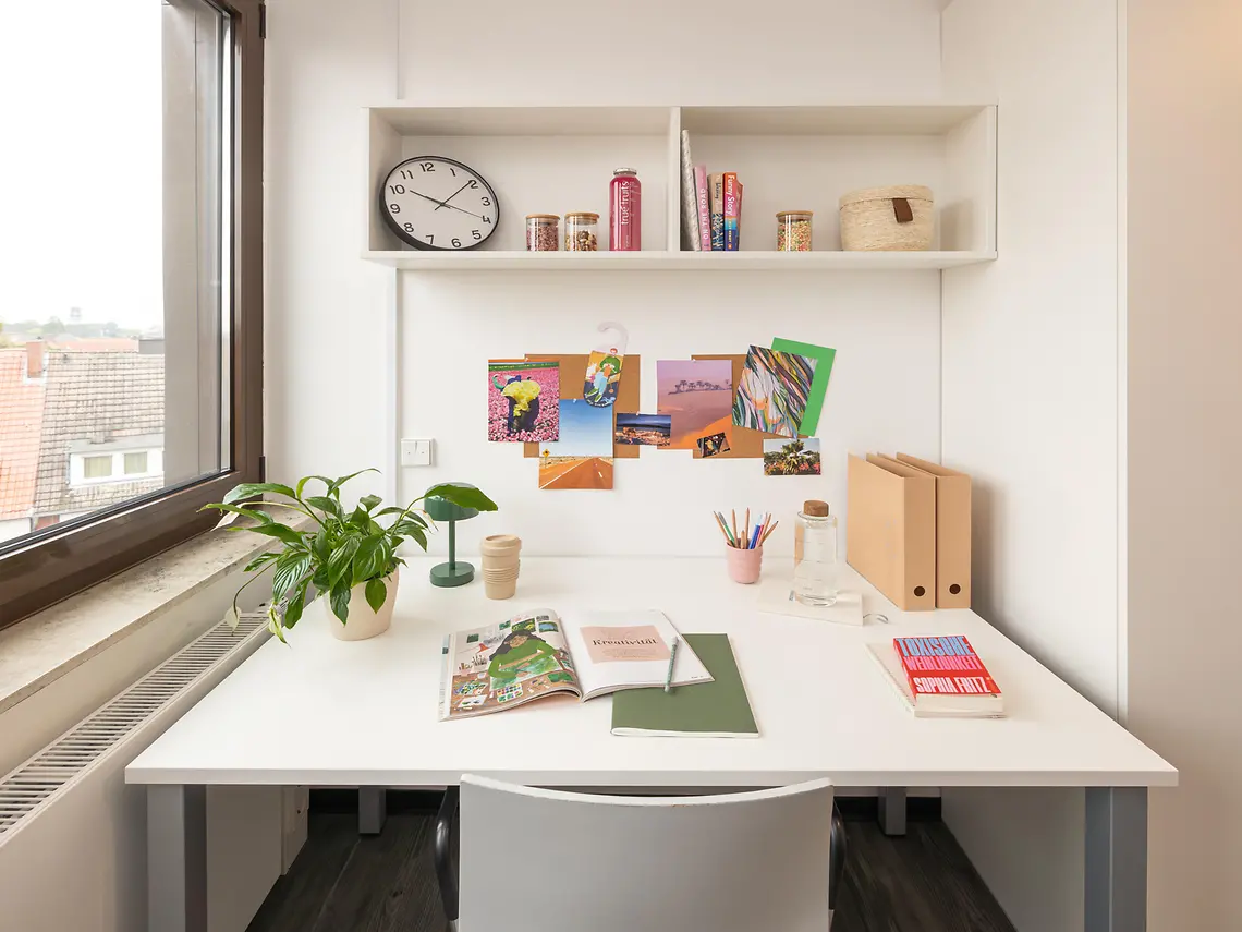 Dedicated study space in a student studio in Münster with desk, shelving and natural light