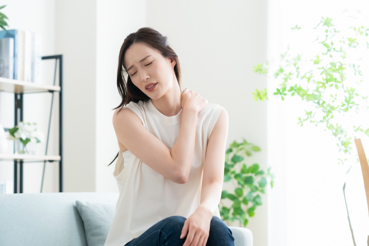 肩を押さえて苦しそうにする女性