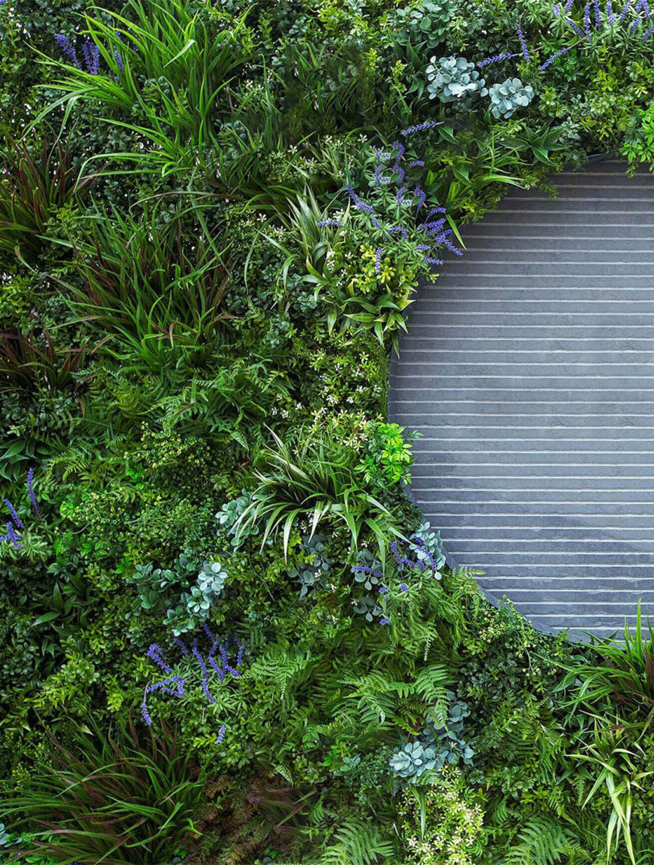 A life-like artificial green wall made of synthetic flowers and artificial grass by AGL Grass.