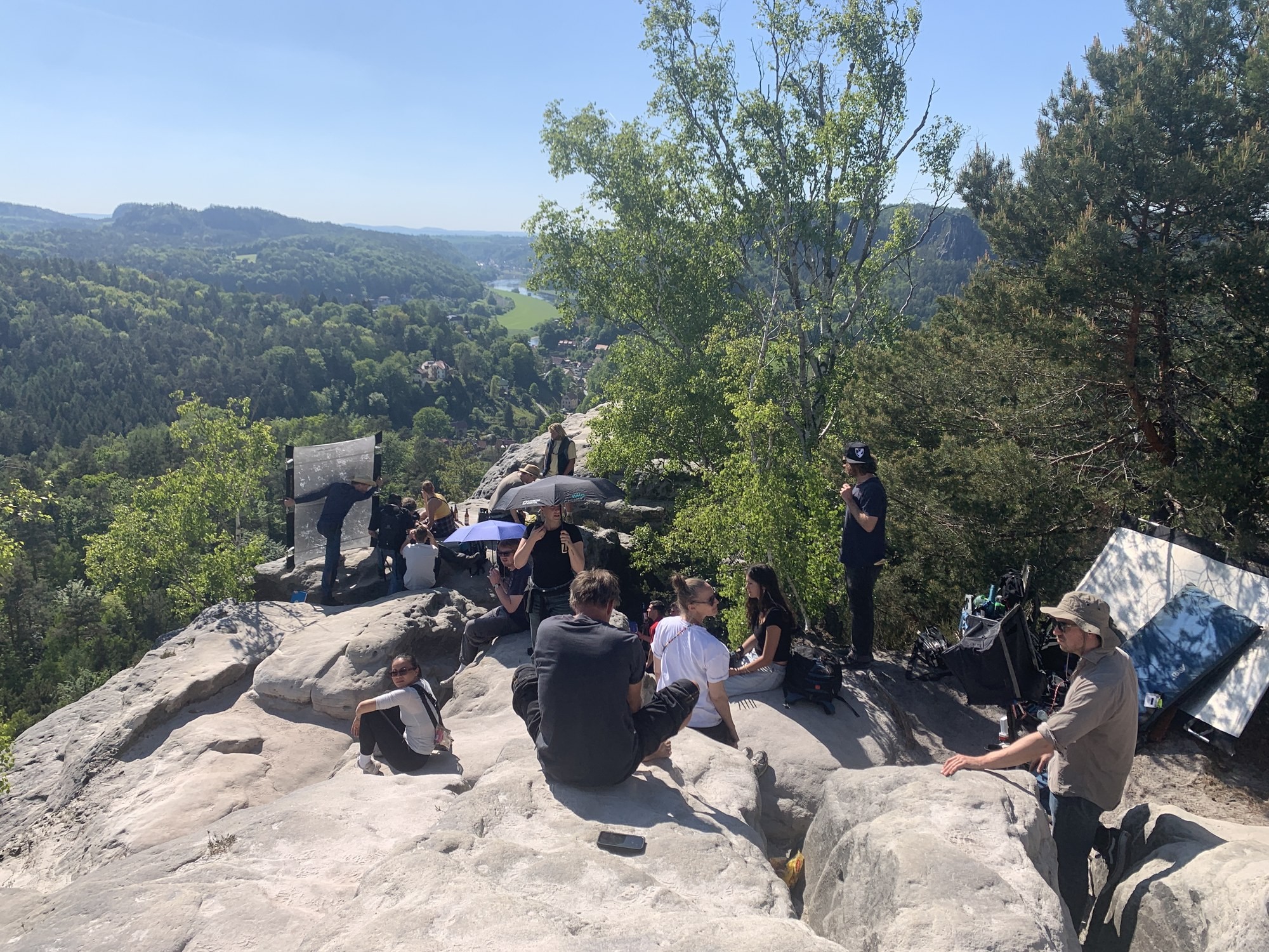 Filming location in Saxon Switzerland: film crew with reflectors on the rock plateau, Elbe Sandstone Mountains panorama behind