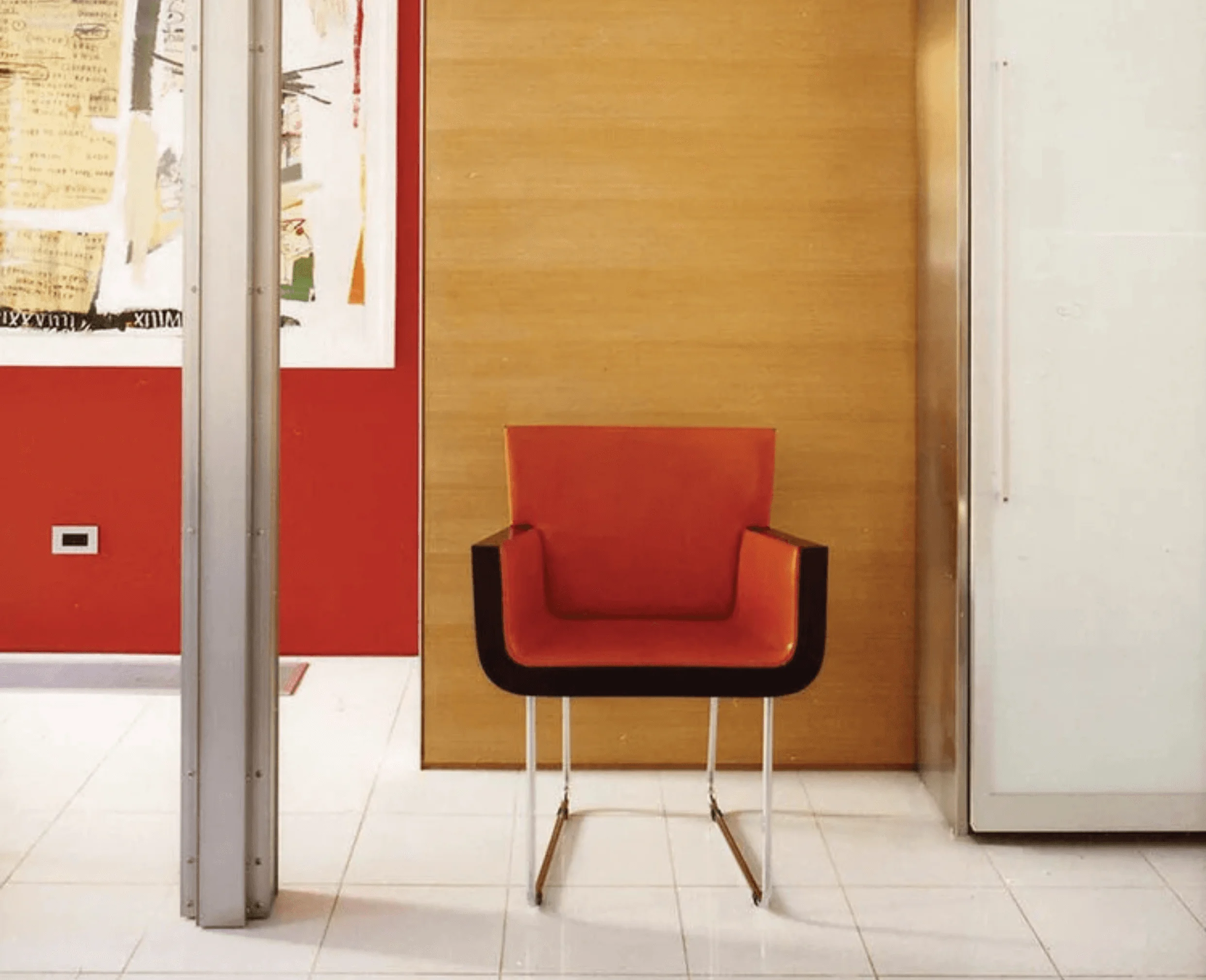 A single orange leather chair rests against a wood-paneled wall