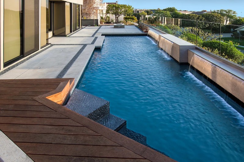 Beautiful picture of the long, geometric pool with waterfall features and IPE deck for the Harbor Ridge Modern Remodel Project