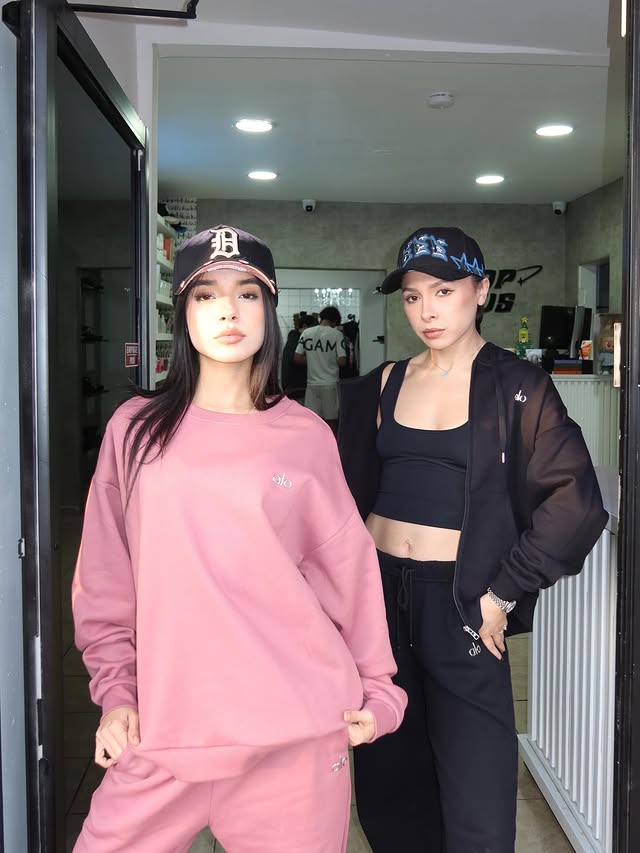 A woman in a colorful patterned shirt and jeans sits on a couch