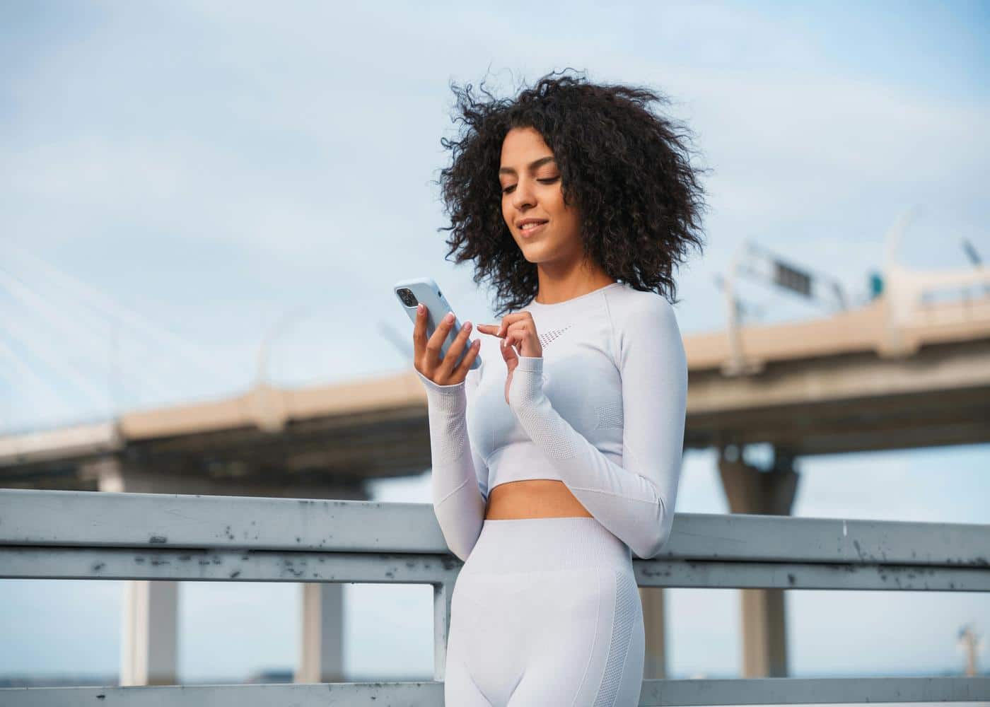 Smiling woman with workout clothes looking at smartphone