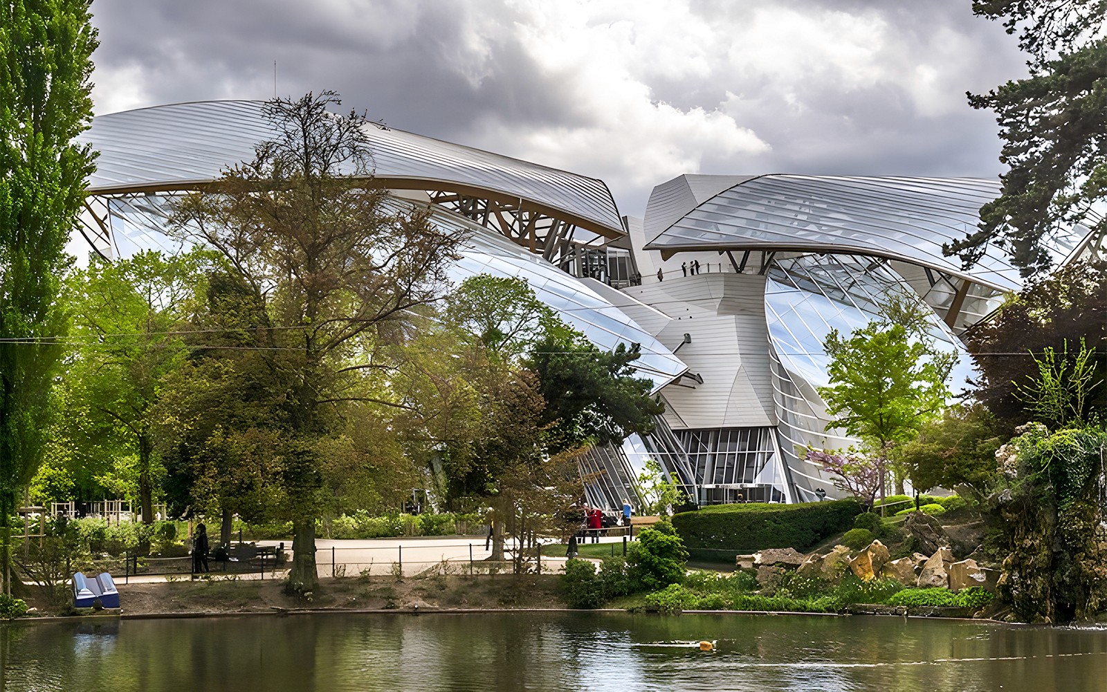 Vue de l'architecture de la Fondation Louis Vuitton avec les arbres environnants, Paris, depuis un étang.