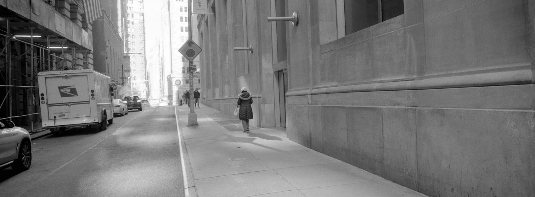 An overexposed panormic black and white image of a street with someone walking down the street
