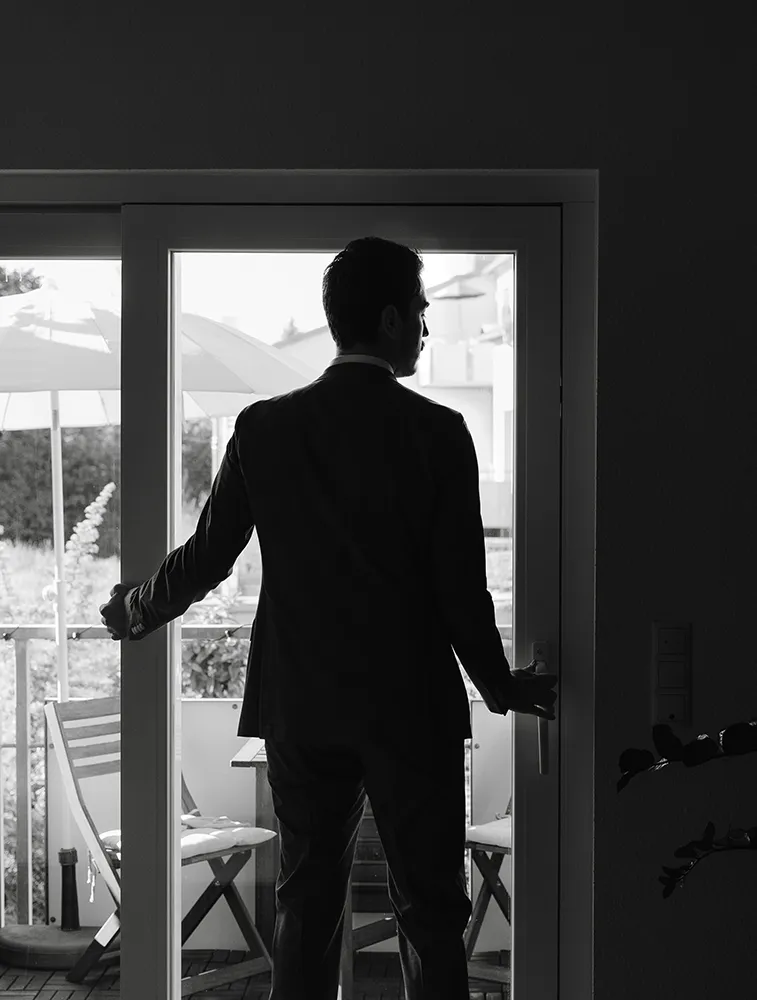 Bräutigam als Silhouette in der Türöffnung beim Getting Ready, Schwarz-Weiß-Hochzeitsfotografie von Eva Sitko