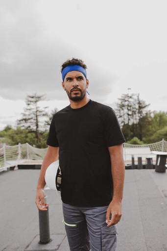 Travailleur de chantier portant le bandana rafraîchissant G-Heat bleu avec casque sous le bras sur un toit